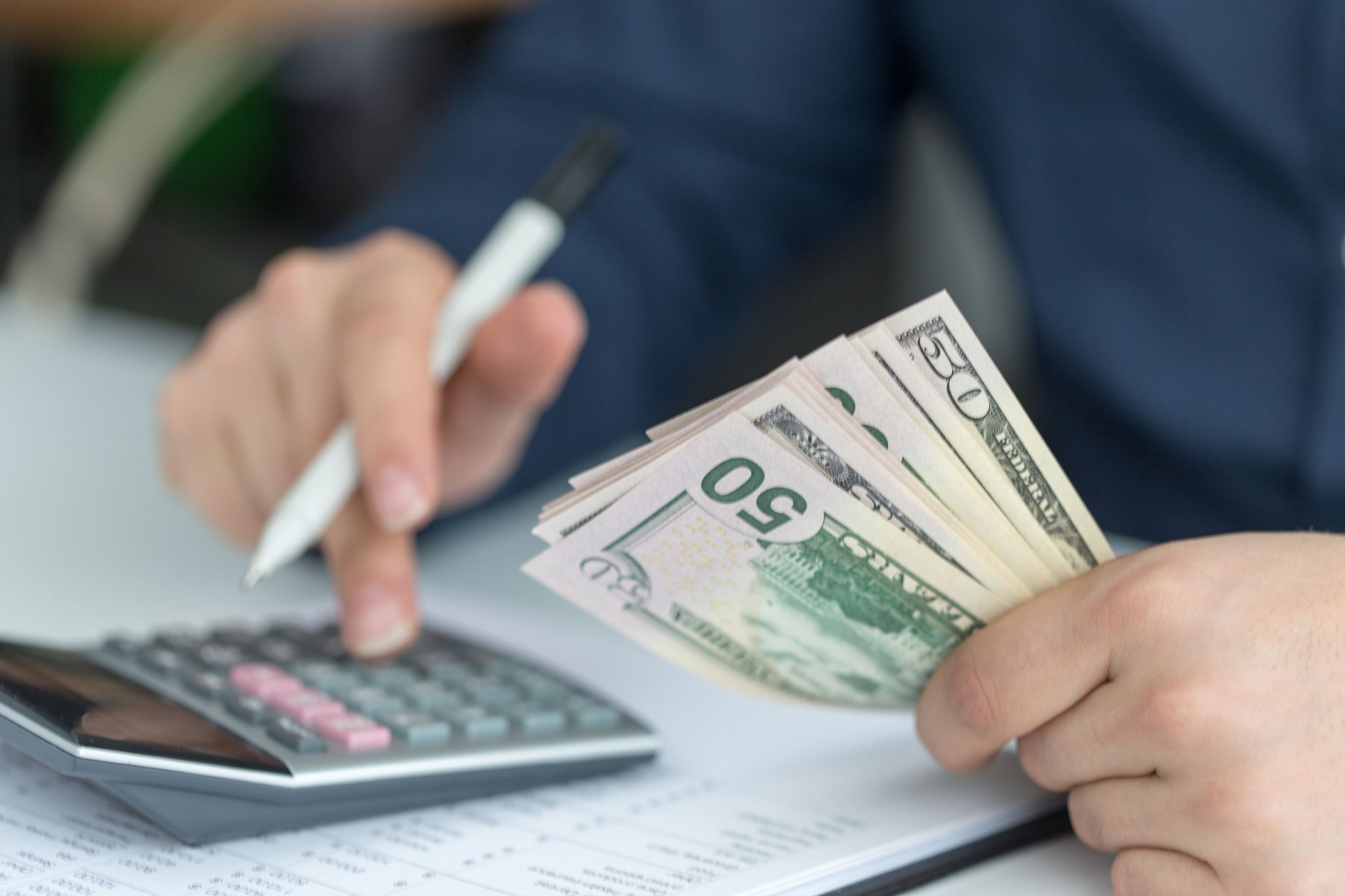 man counting money with calculator and spreedsheet