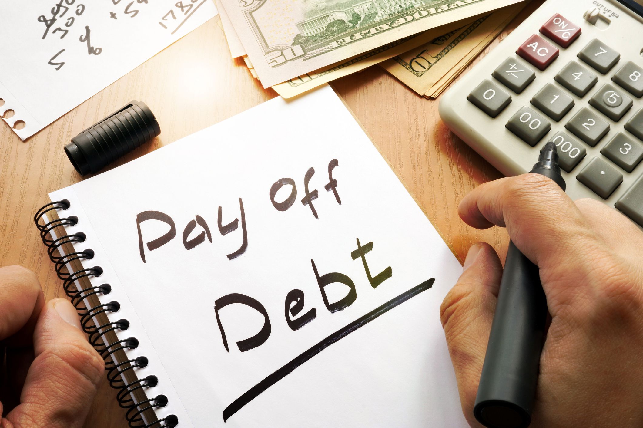 hand with notepad that reads pay off debt