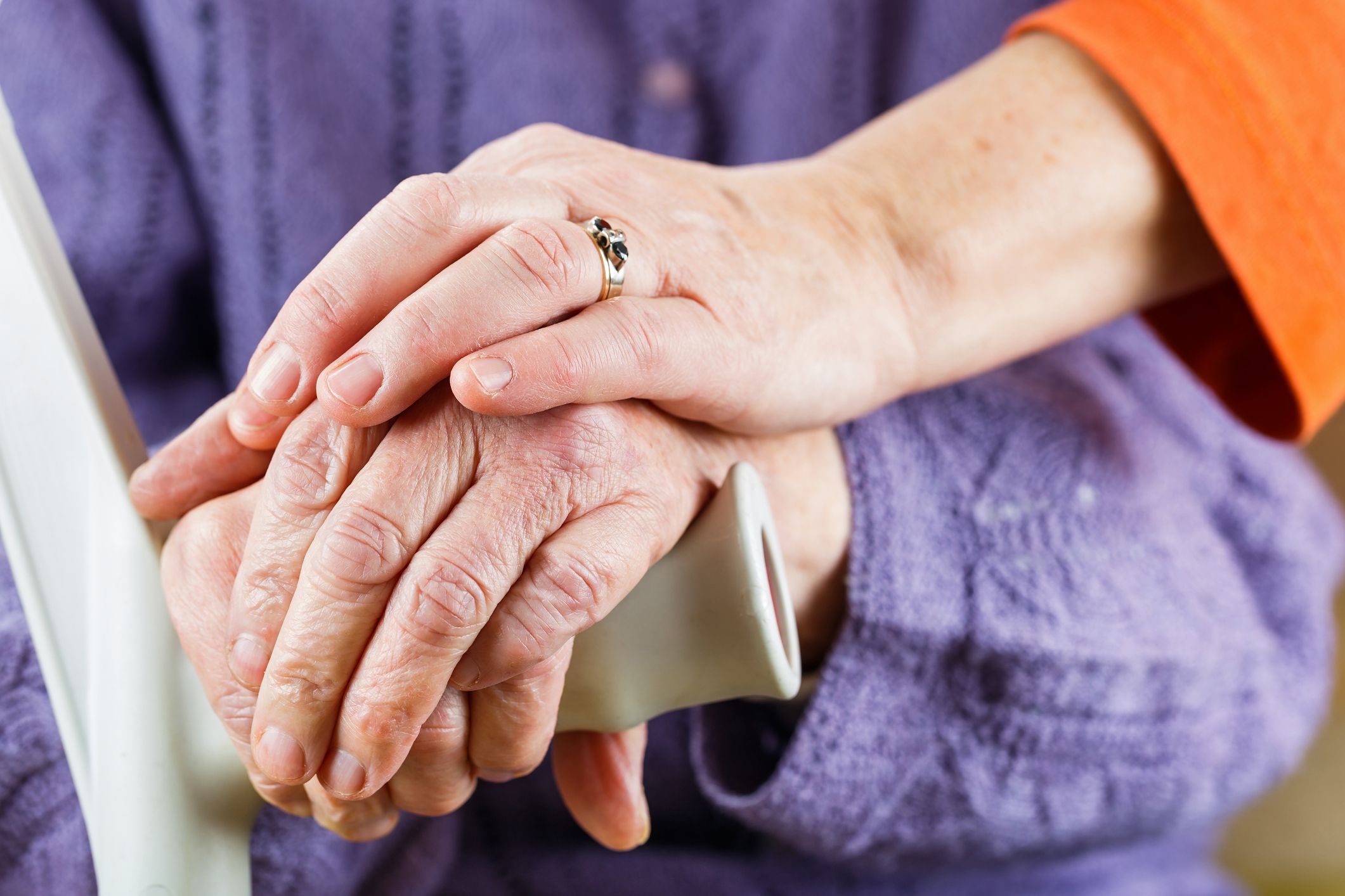 middle aged hands resting over senior hands on walker