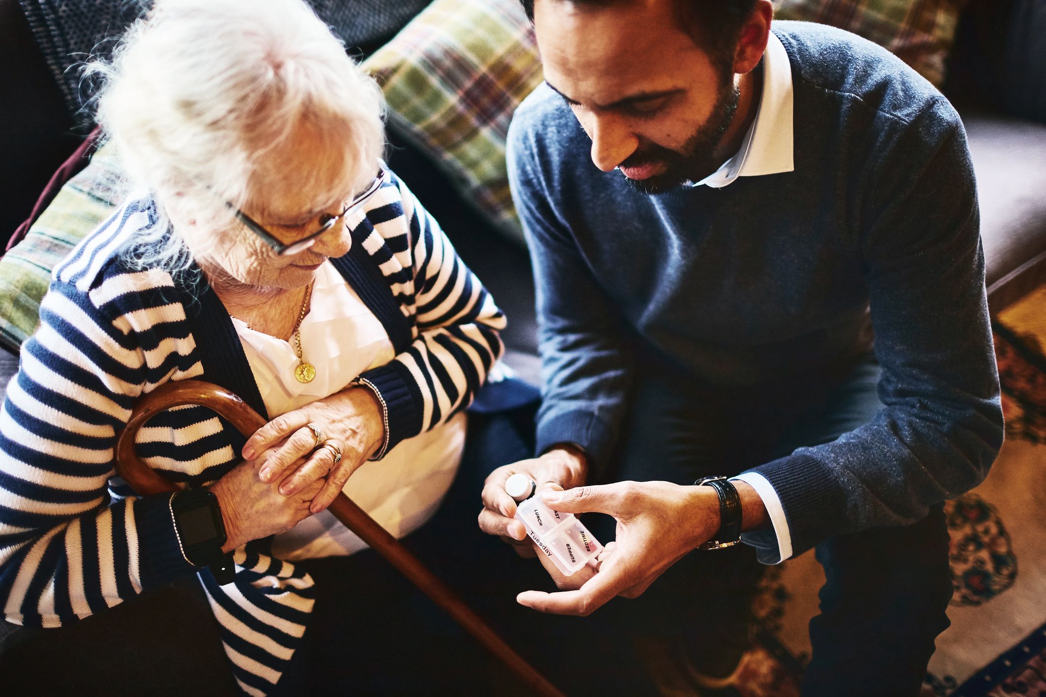 man giving medications to senior woman