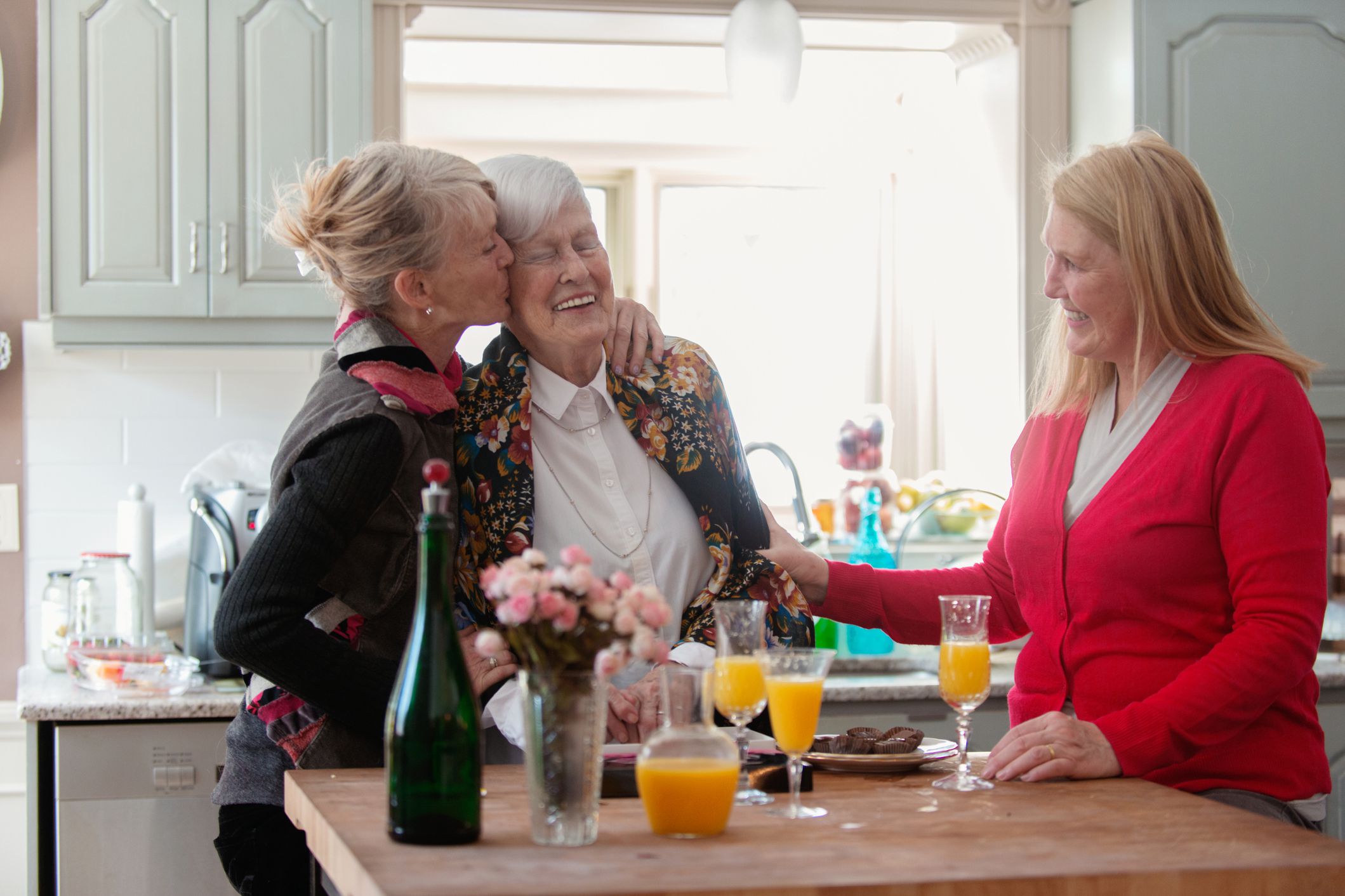 middle-aged women embracing mother in kitchen