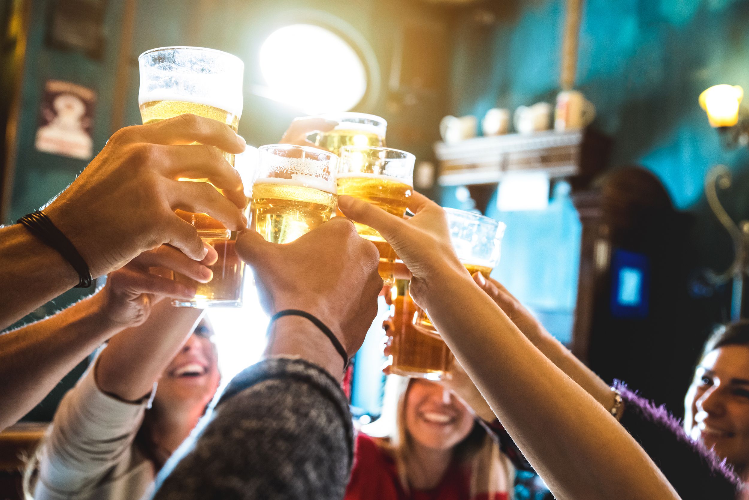group of happy friends drinking and toasting beer at brewery bar restaurant