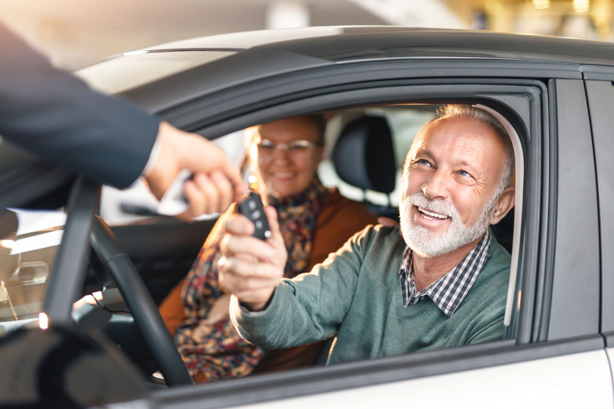 senior couple getting keys in rental car