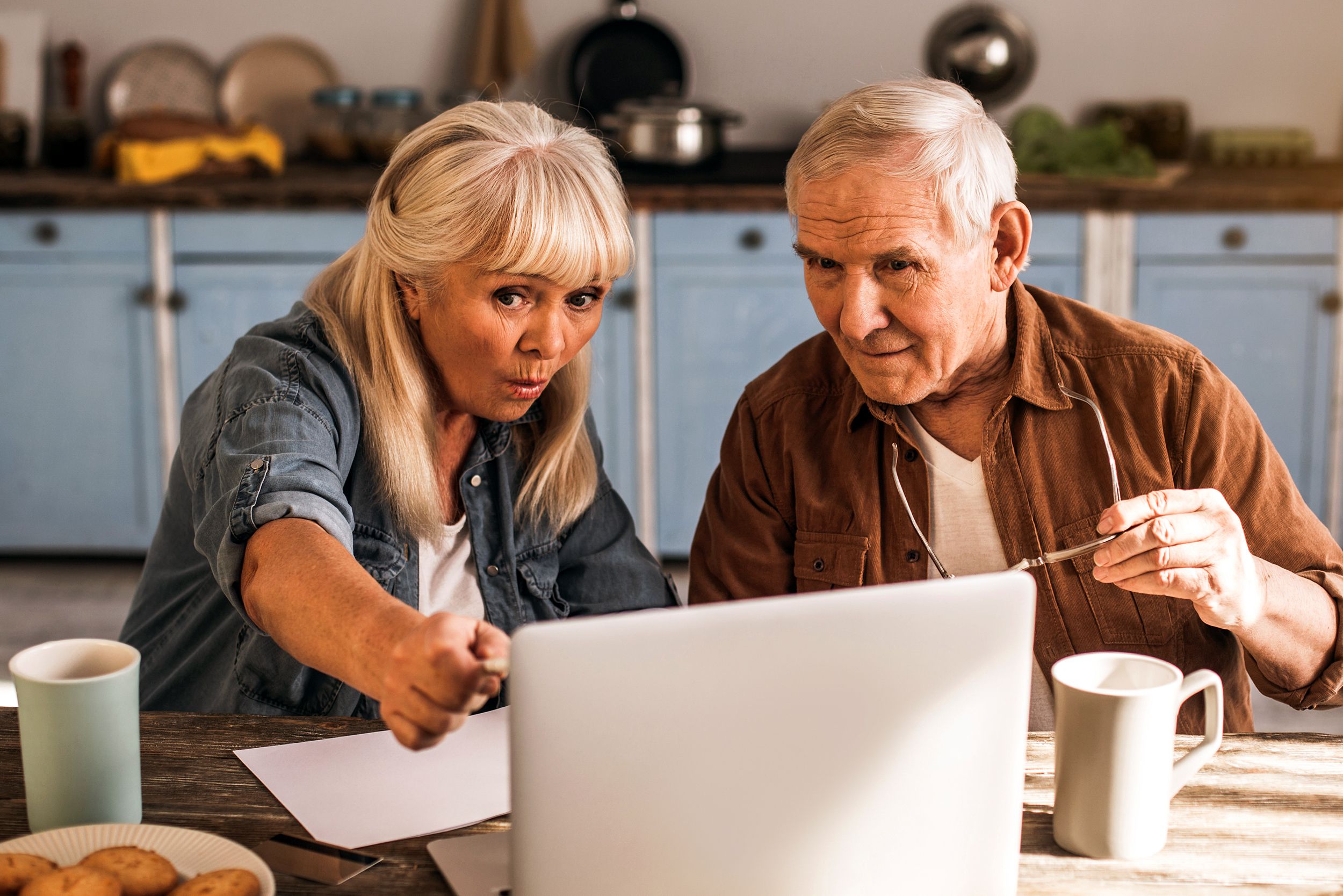 mature husband and wife using modern computer at home