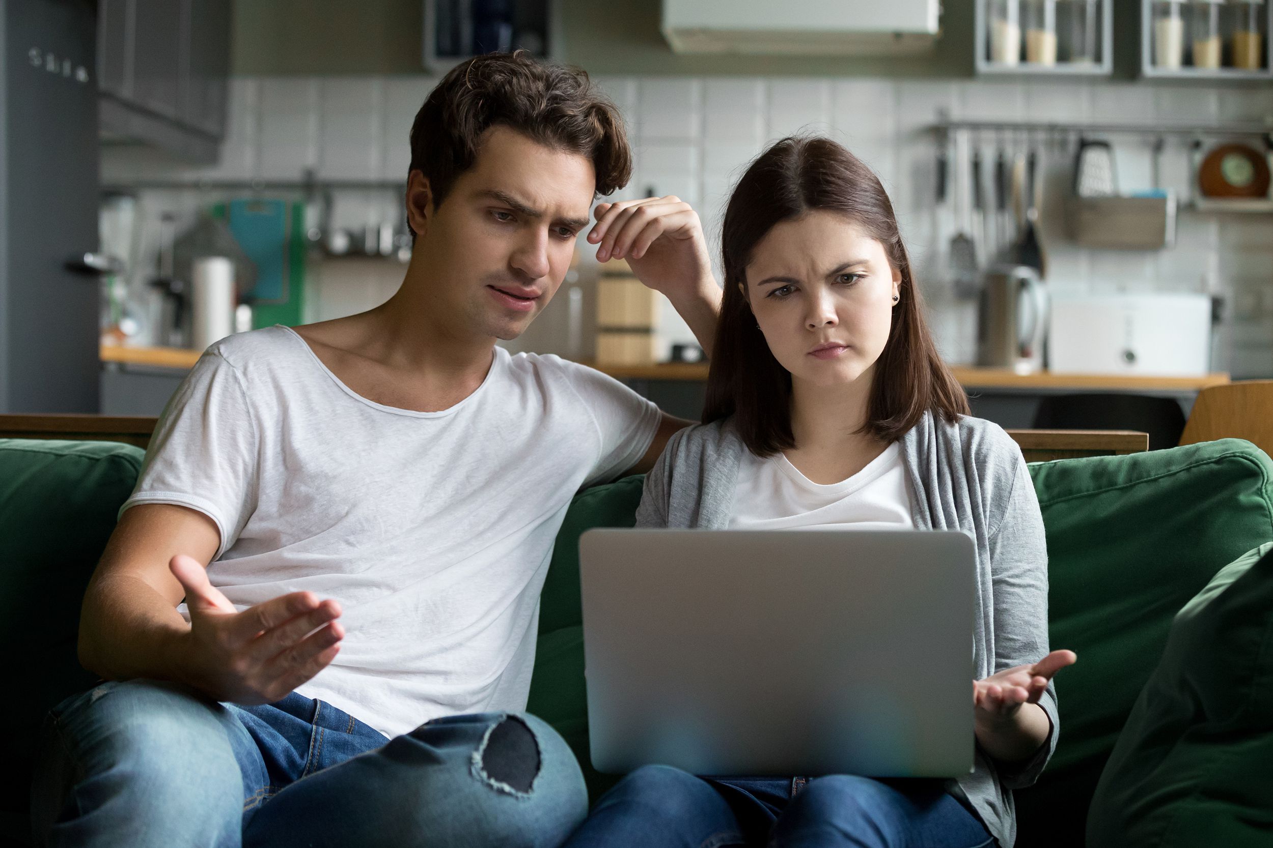 millennial couple annoyed by stuck laptop confused by online news