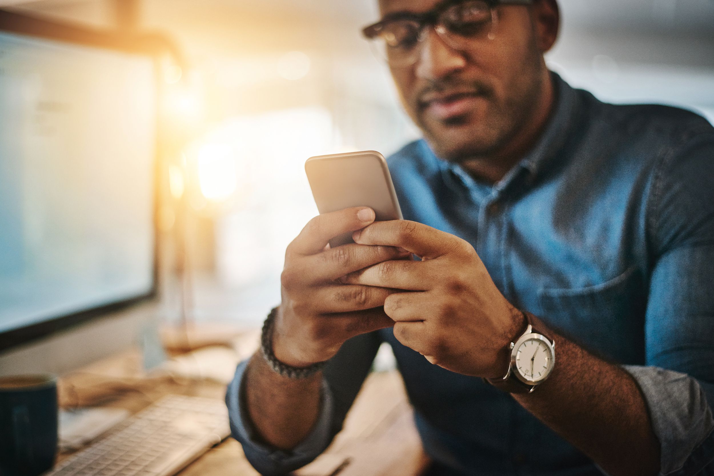 man dialing on mobile, while at his desk