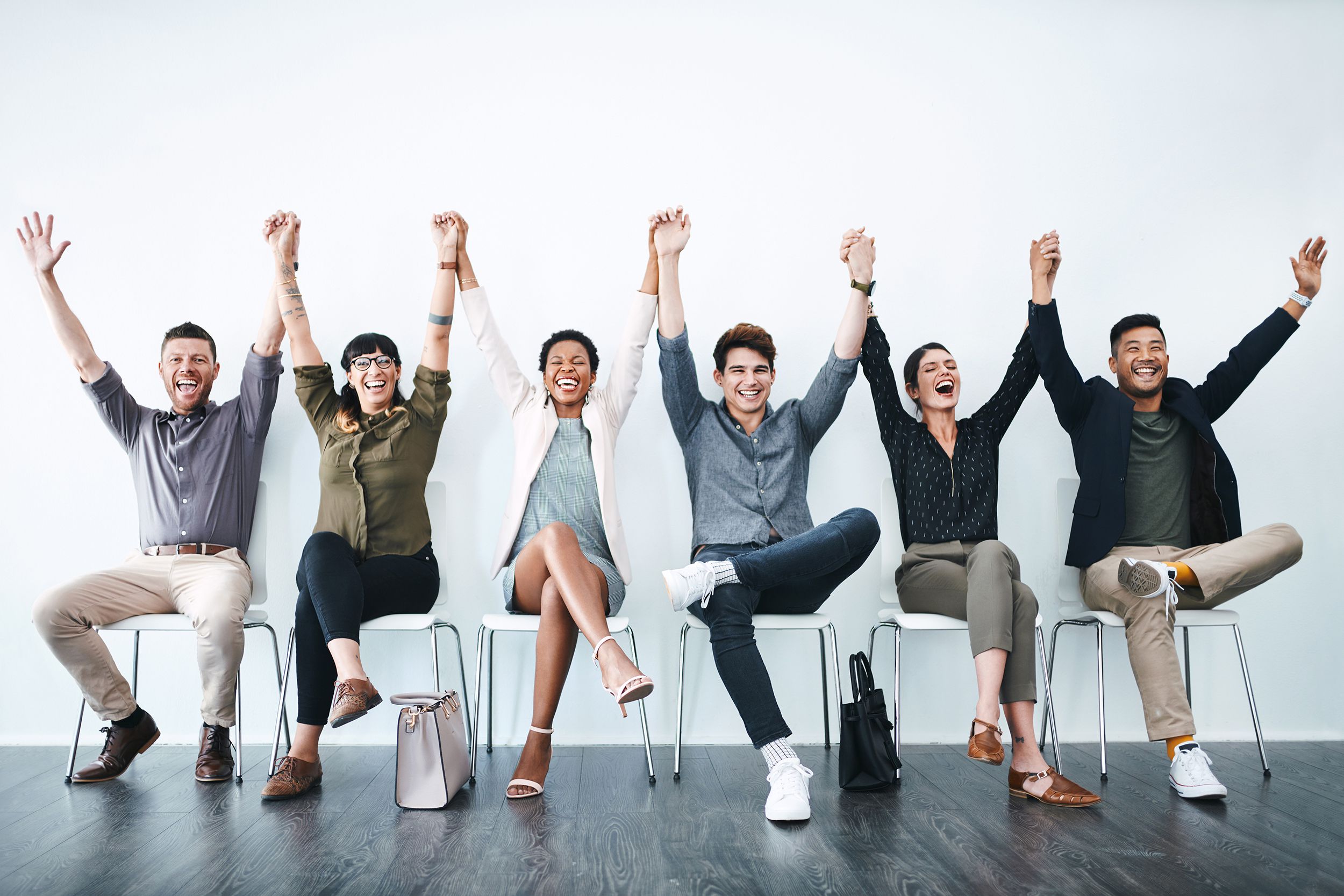 people with hands up, while sitting down all waiting for an interview
