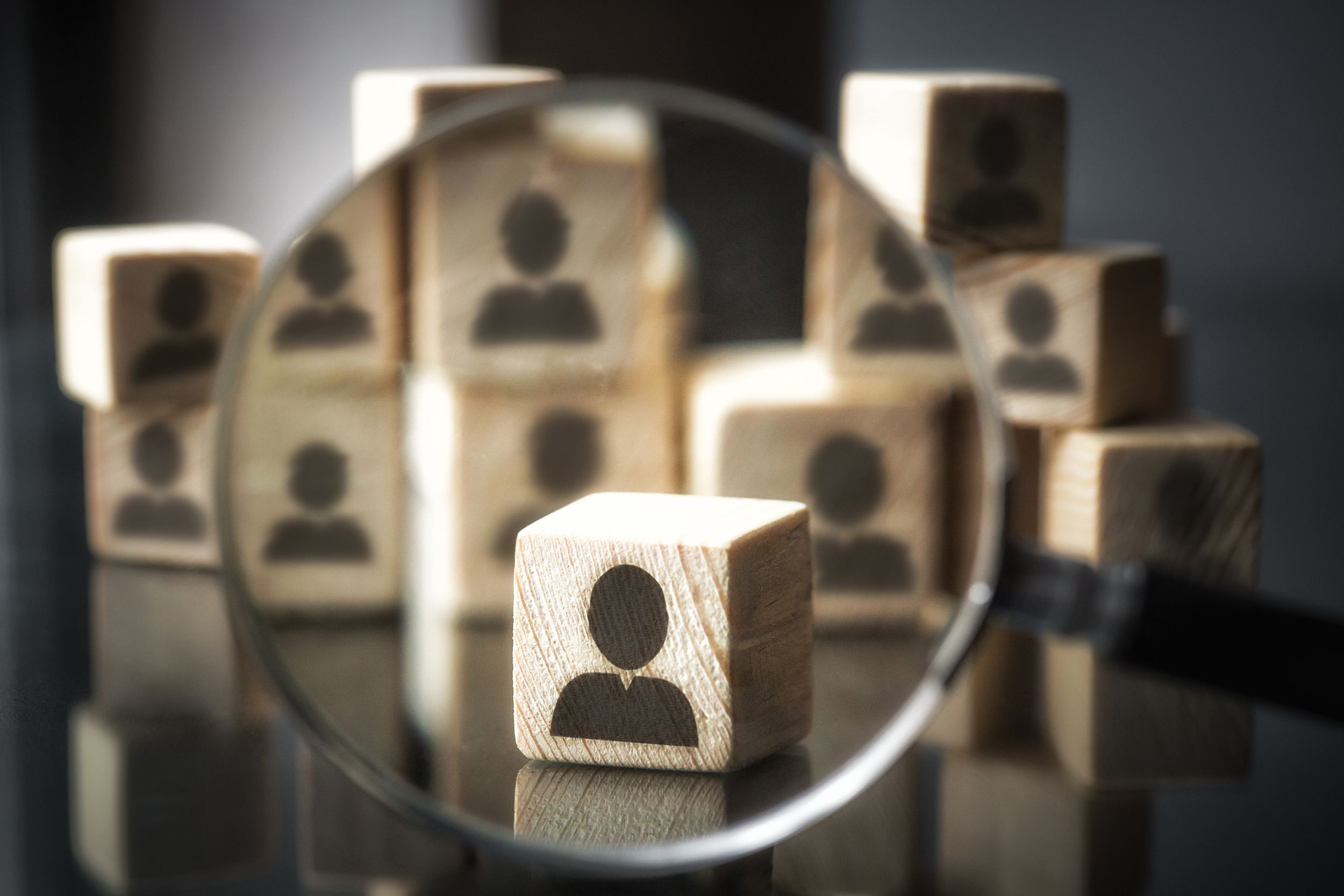 magnifying glass focusing upon blocks with little profiles of people