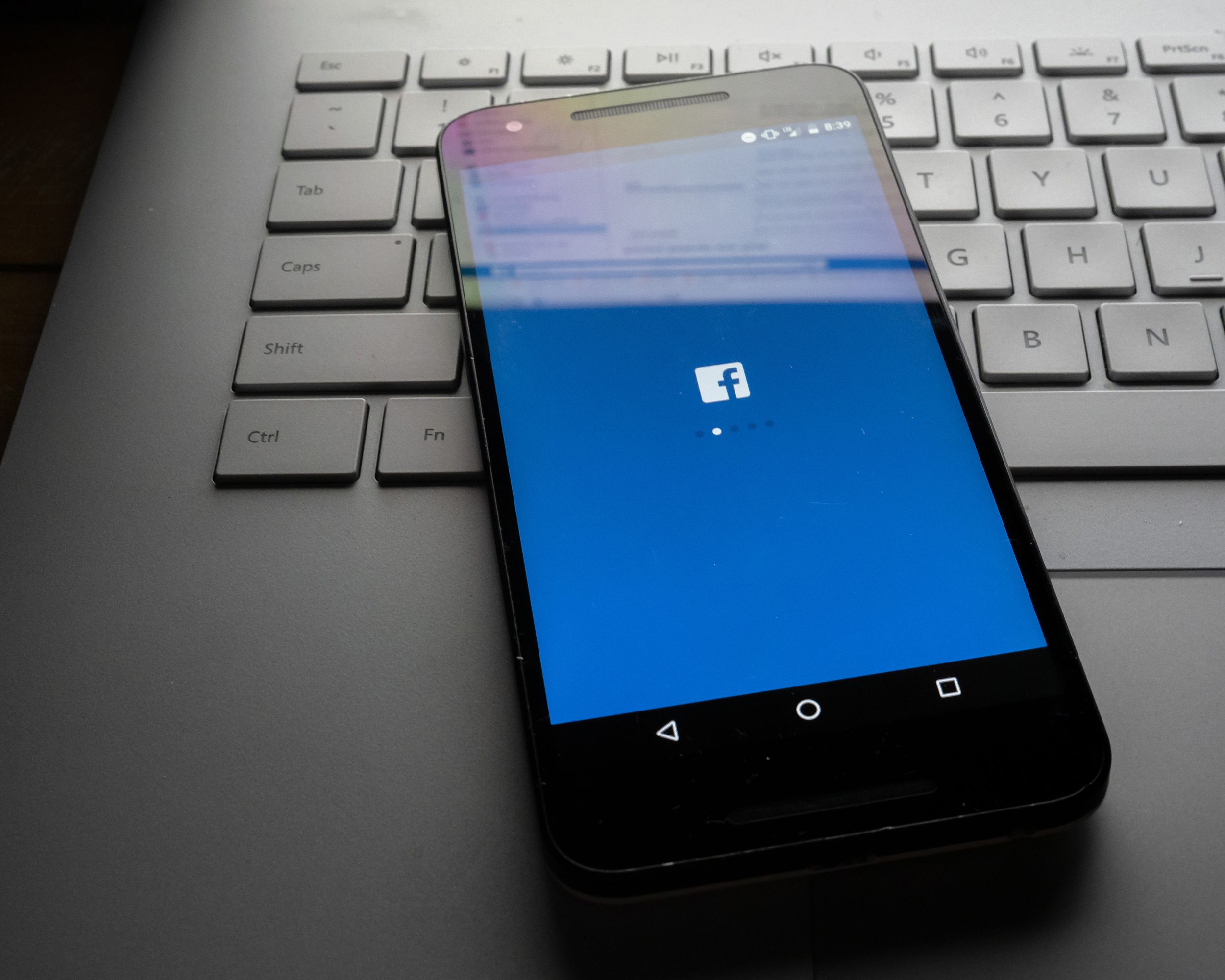 phone sitting on laptop with Facebook desktop site sitting on screen