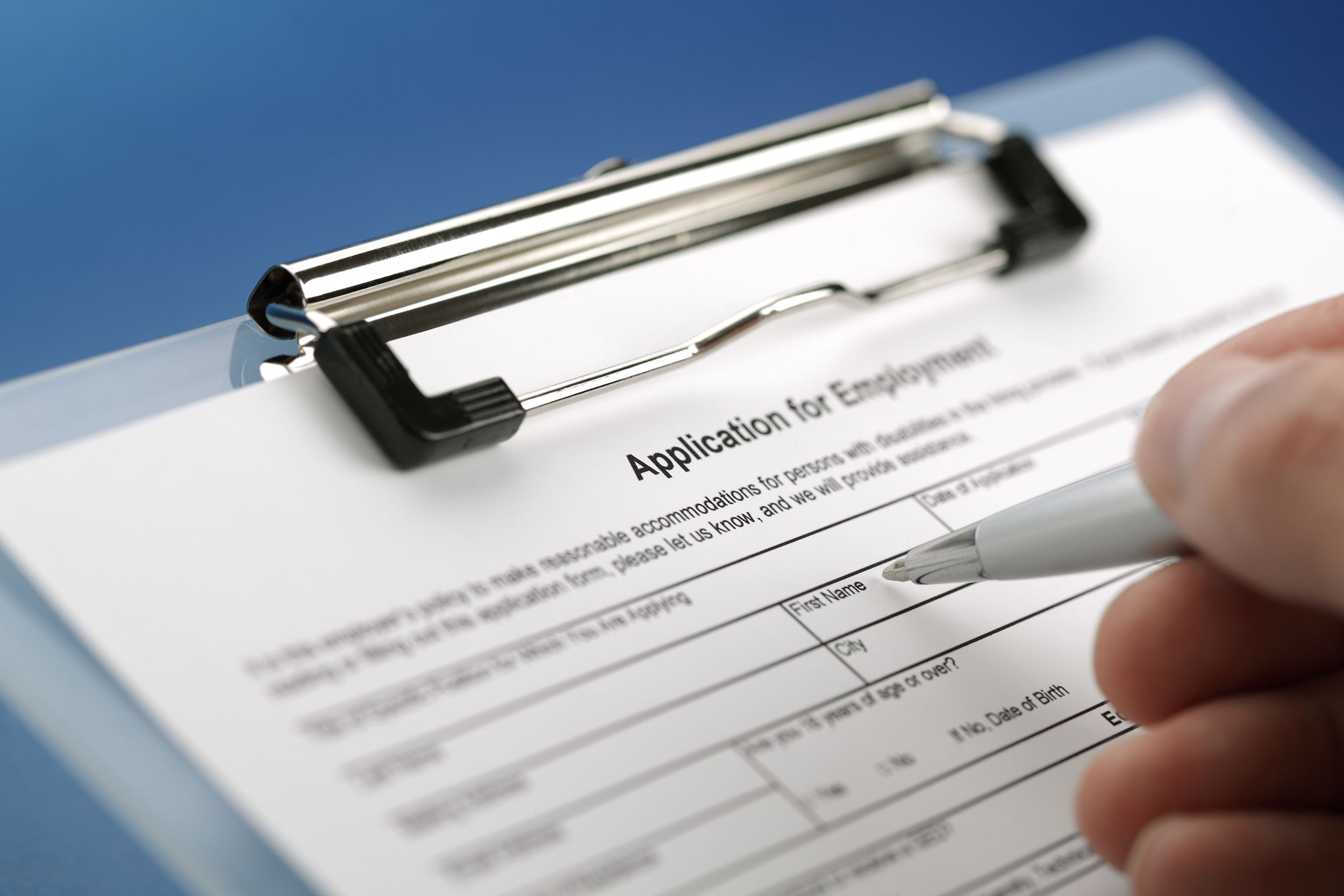close-up of a hand holding a pen to an employee application