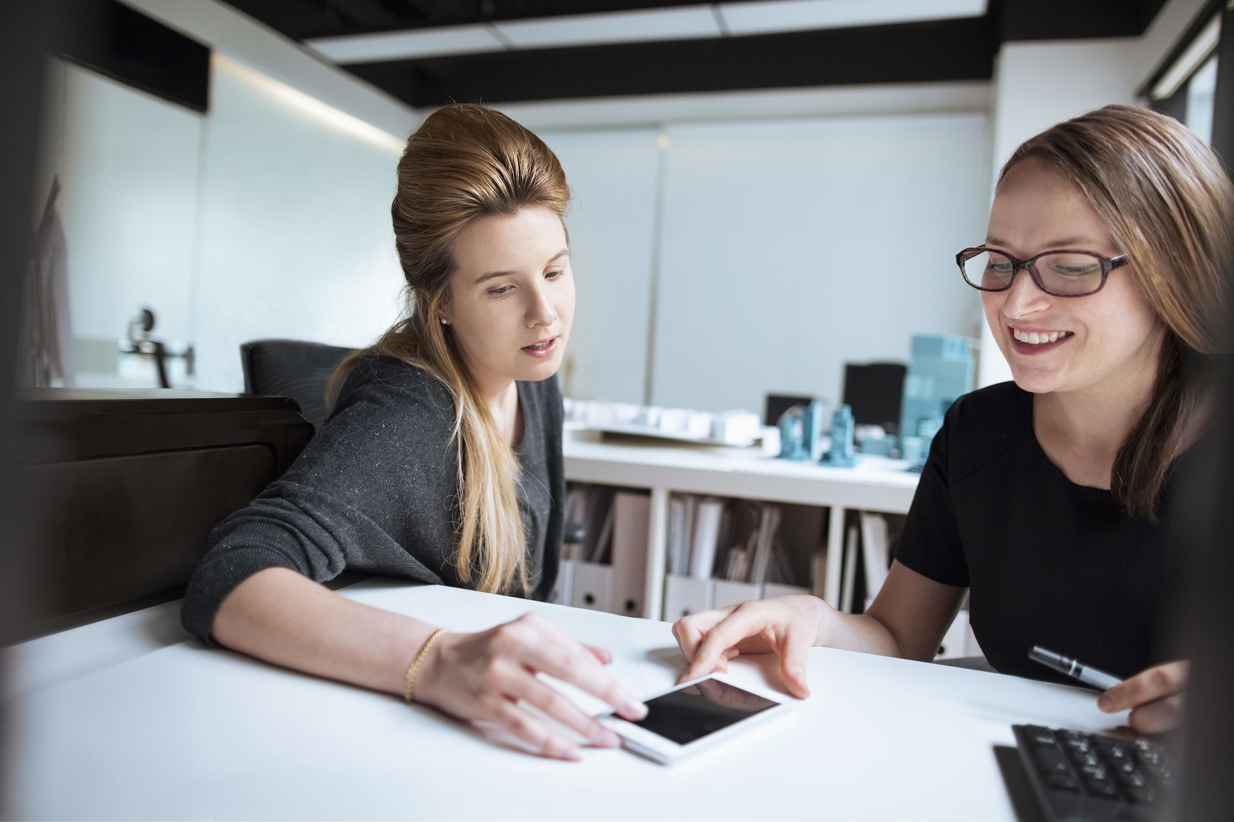 women looking at ideas on smart phone together in office