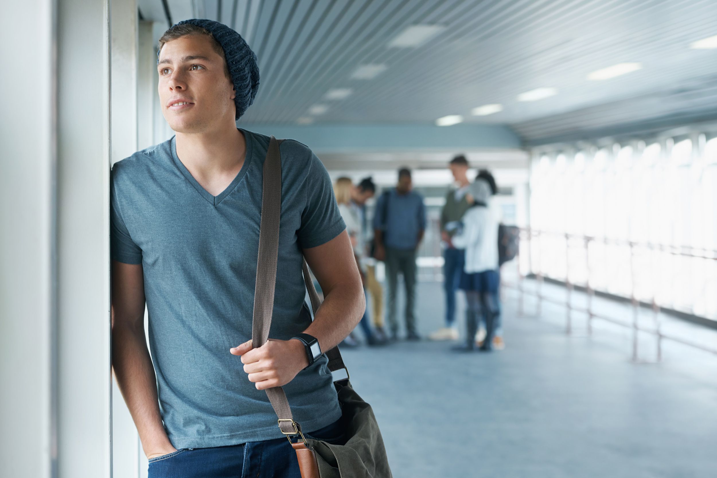 young man looking out of the window, with group of people in the background