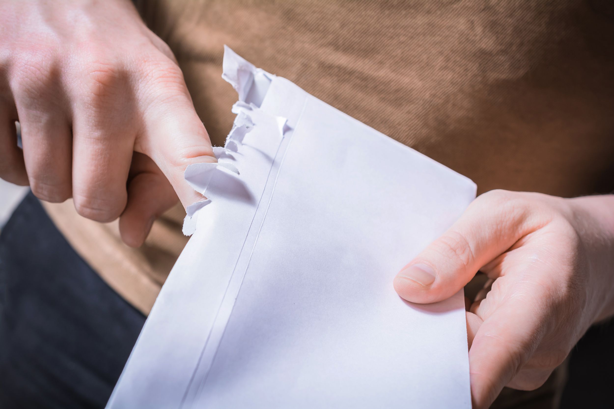 male hands ripping open the edge of an envelope