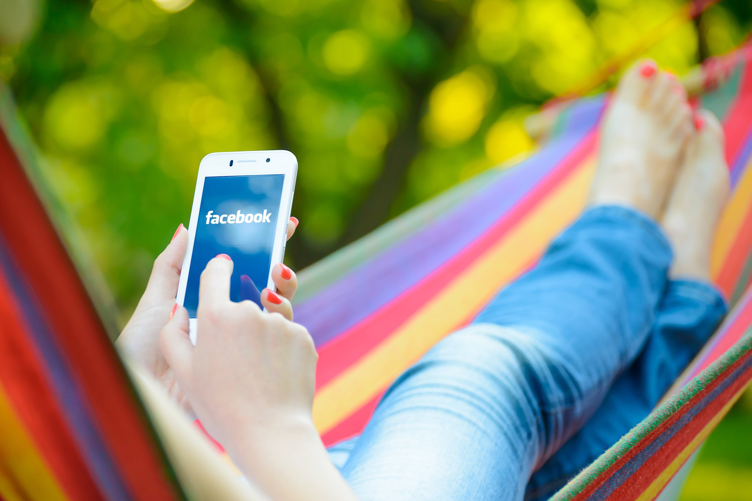 woman in hammock using facebook on mobile phone