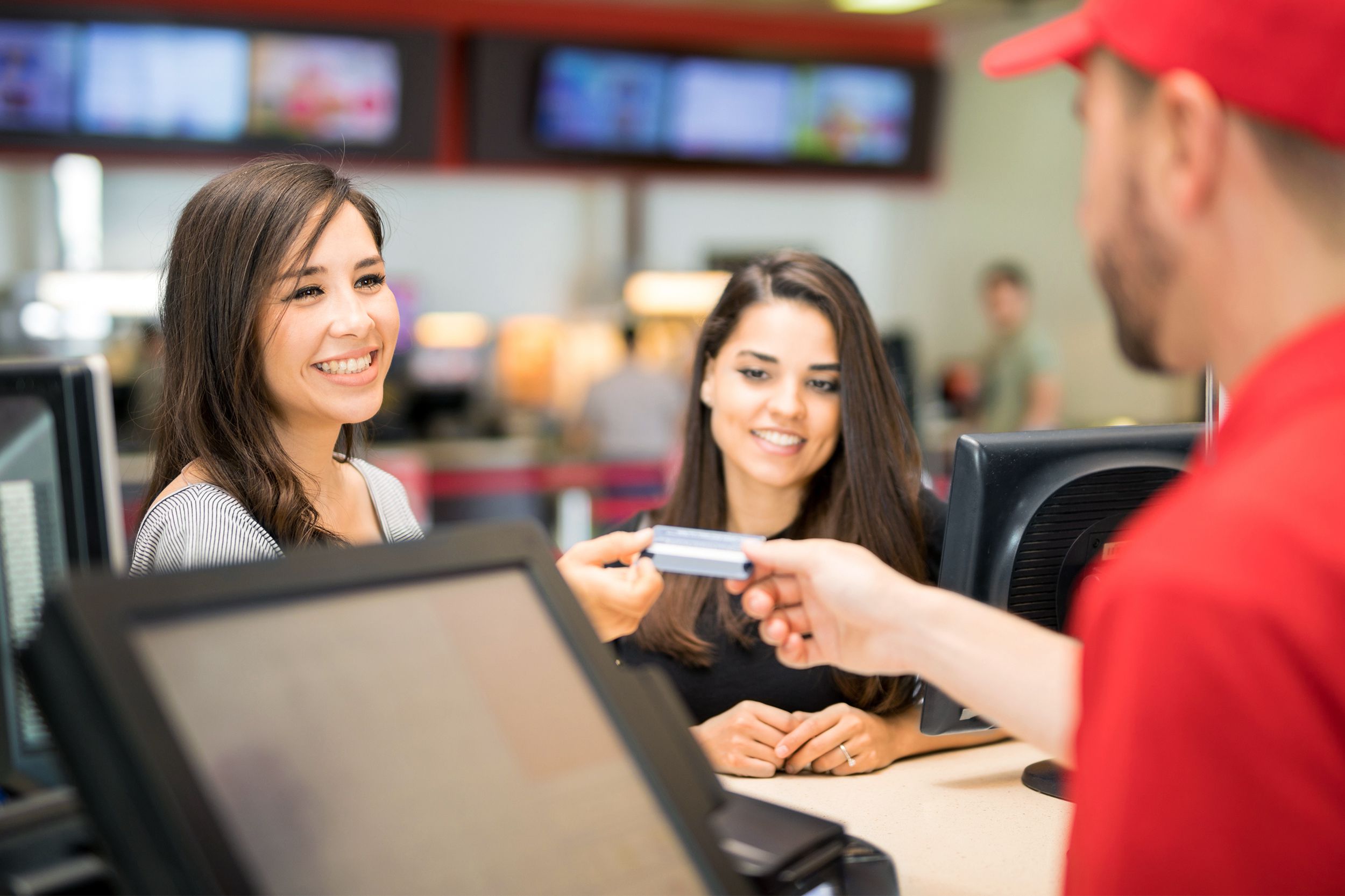 Women at a movie theater concession stand using a credit card
