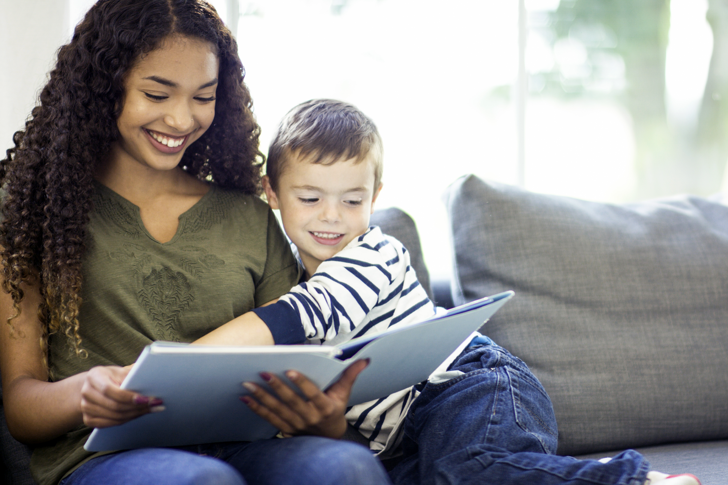 Young woman babysitting a little boy and reading him a book