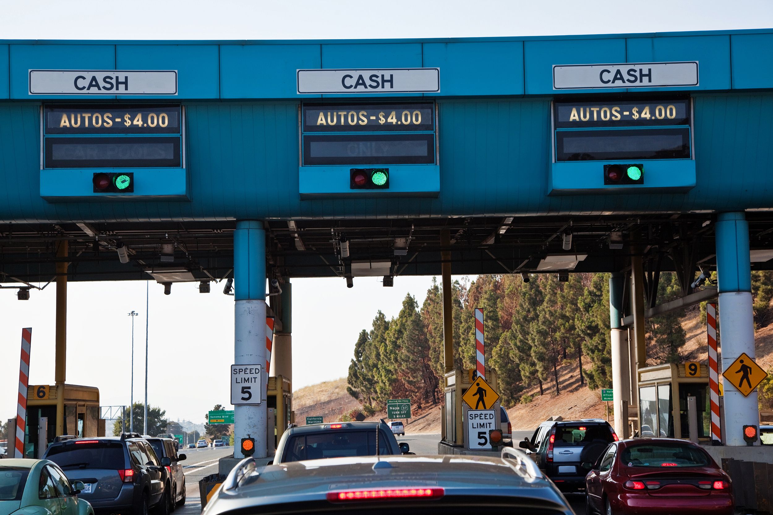 Cars in line at a toll road near San Francisco, three lines, focus on middle line, blue toll area, mountains blurred in the background