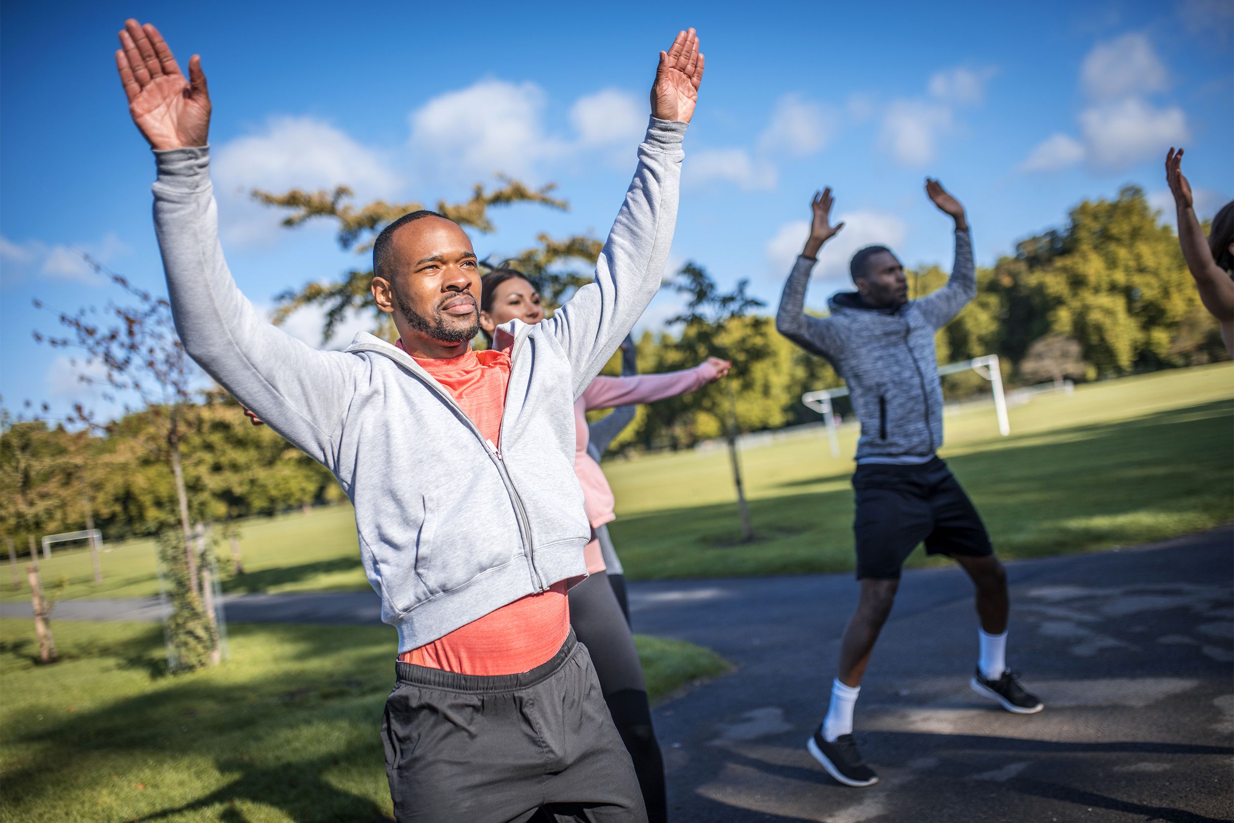 Group of men and women doing jumping jacks outside