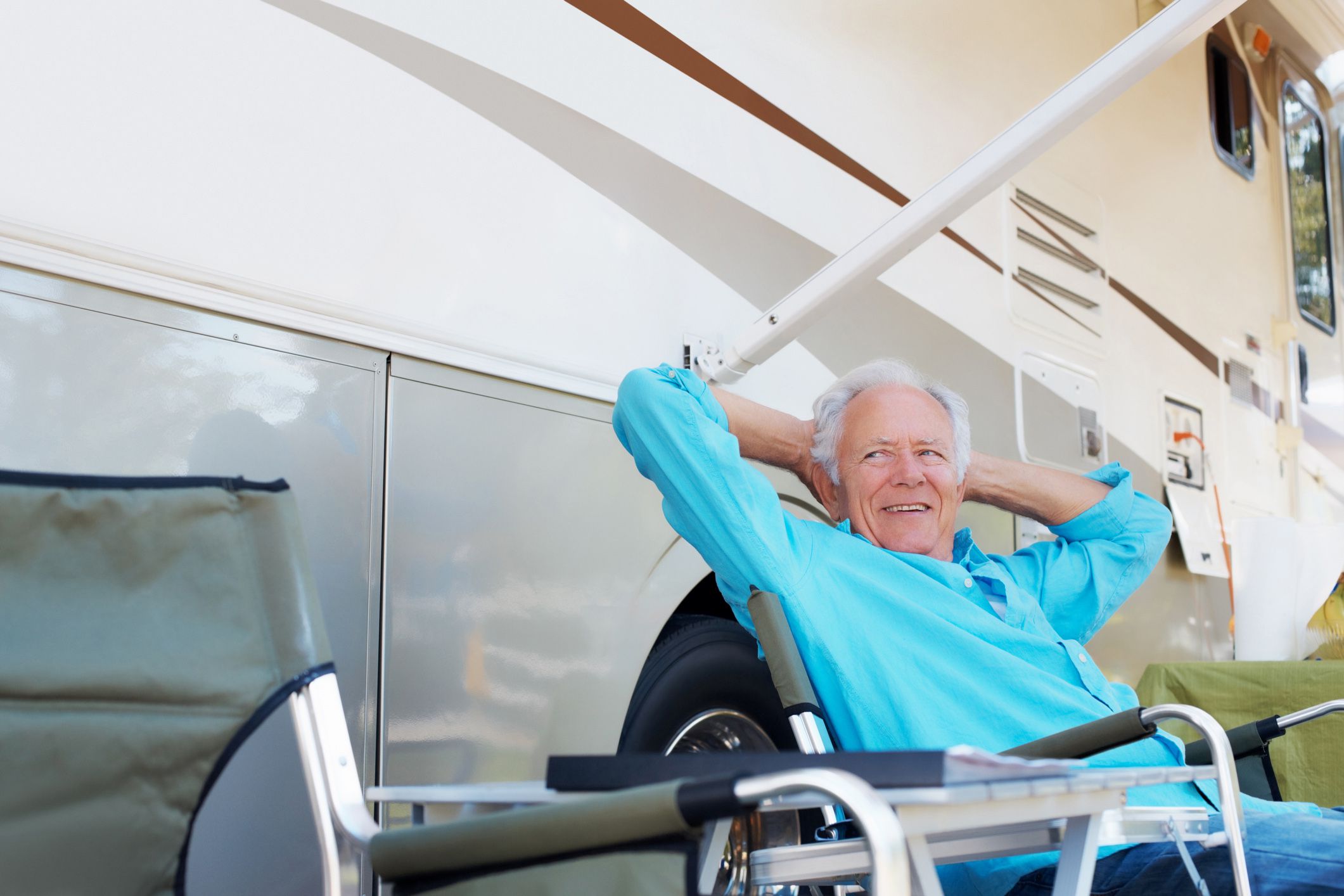 senior man leaning back smiling sitting outside rv