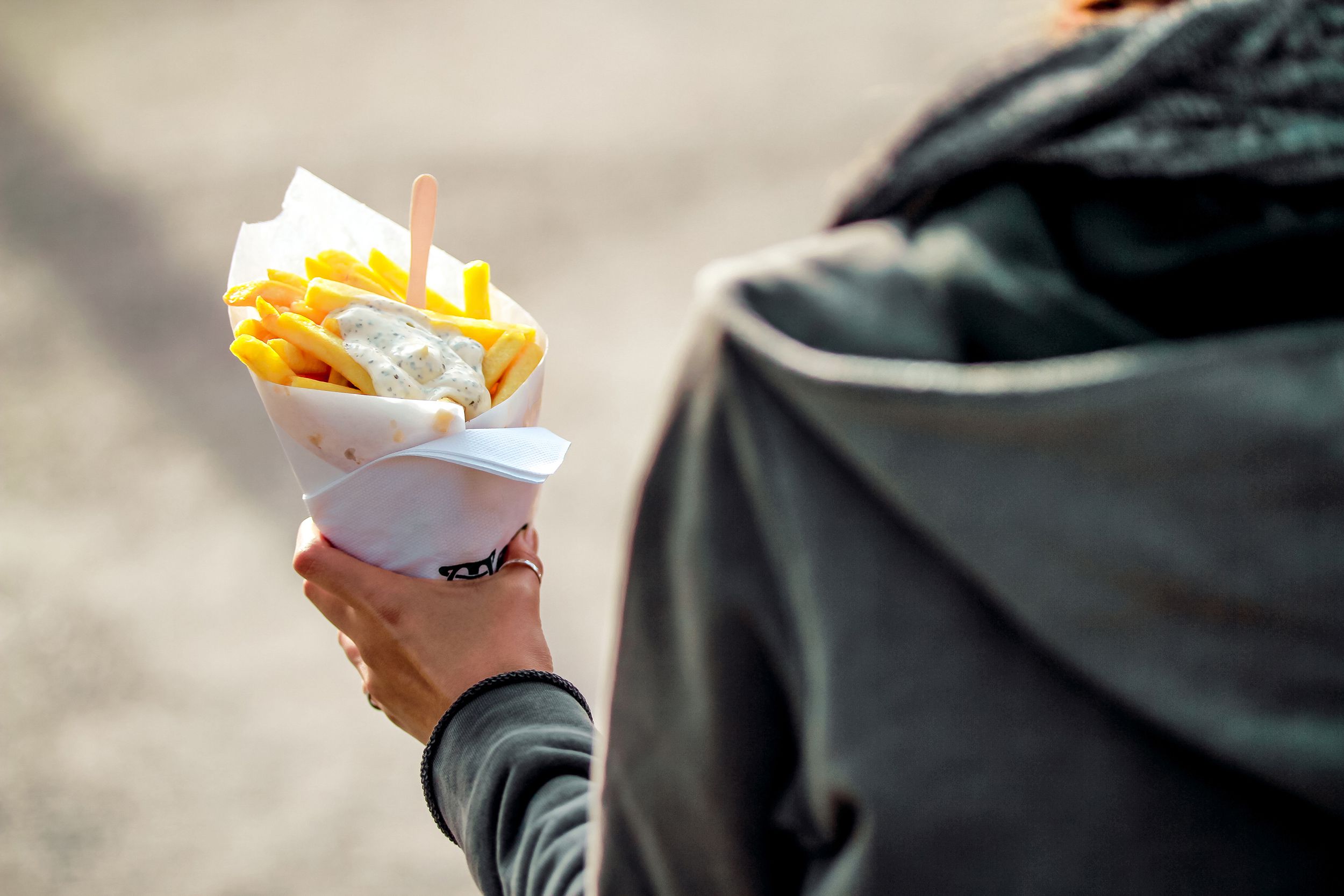 tourist holds belgian fries in hand in the streets of brussels