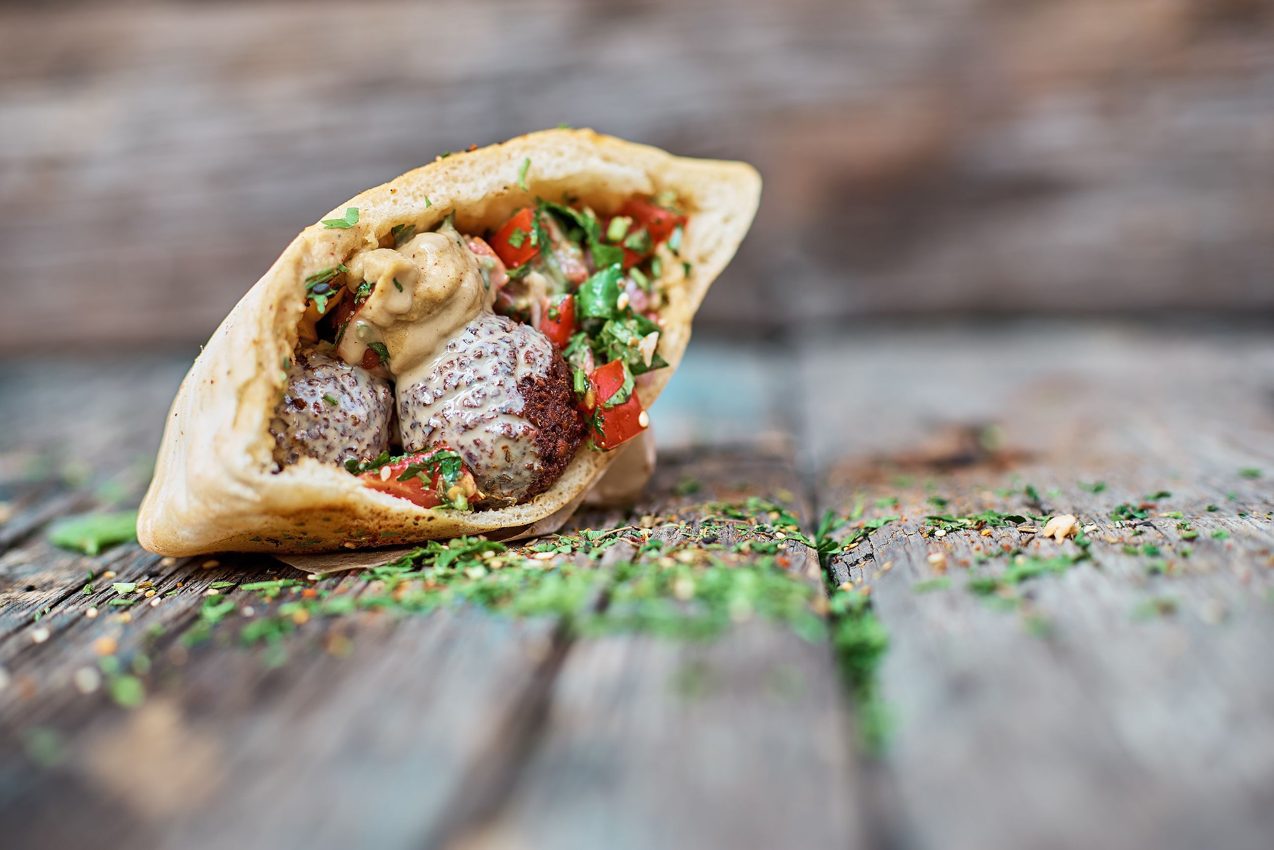 falafel and fresh vegetables in pita bread on wooden table