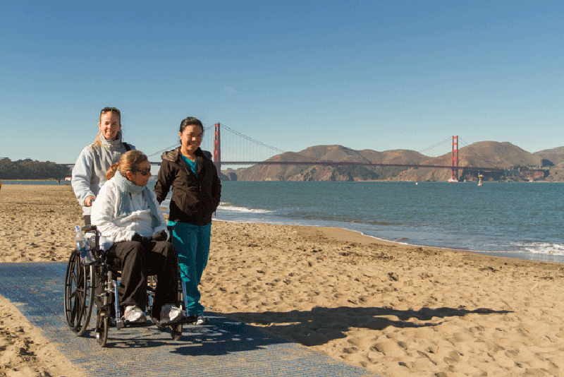 wheelchair person and two friends in park in front of Golden Gate bridge, San Francisco