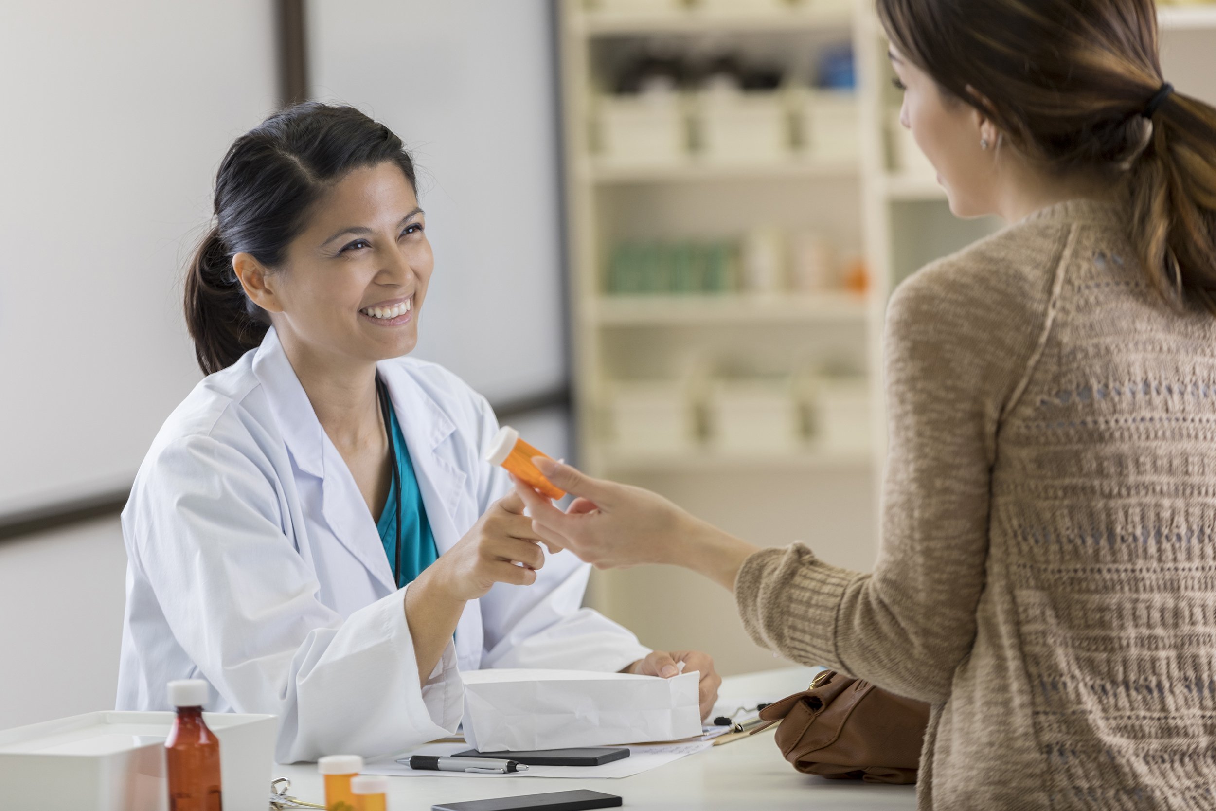 young pharmacy customer asks pharmacist questions about medication