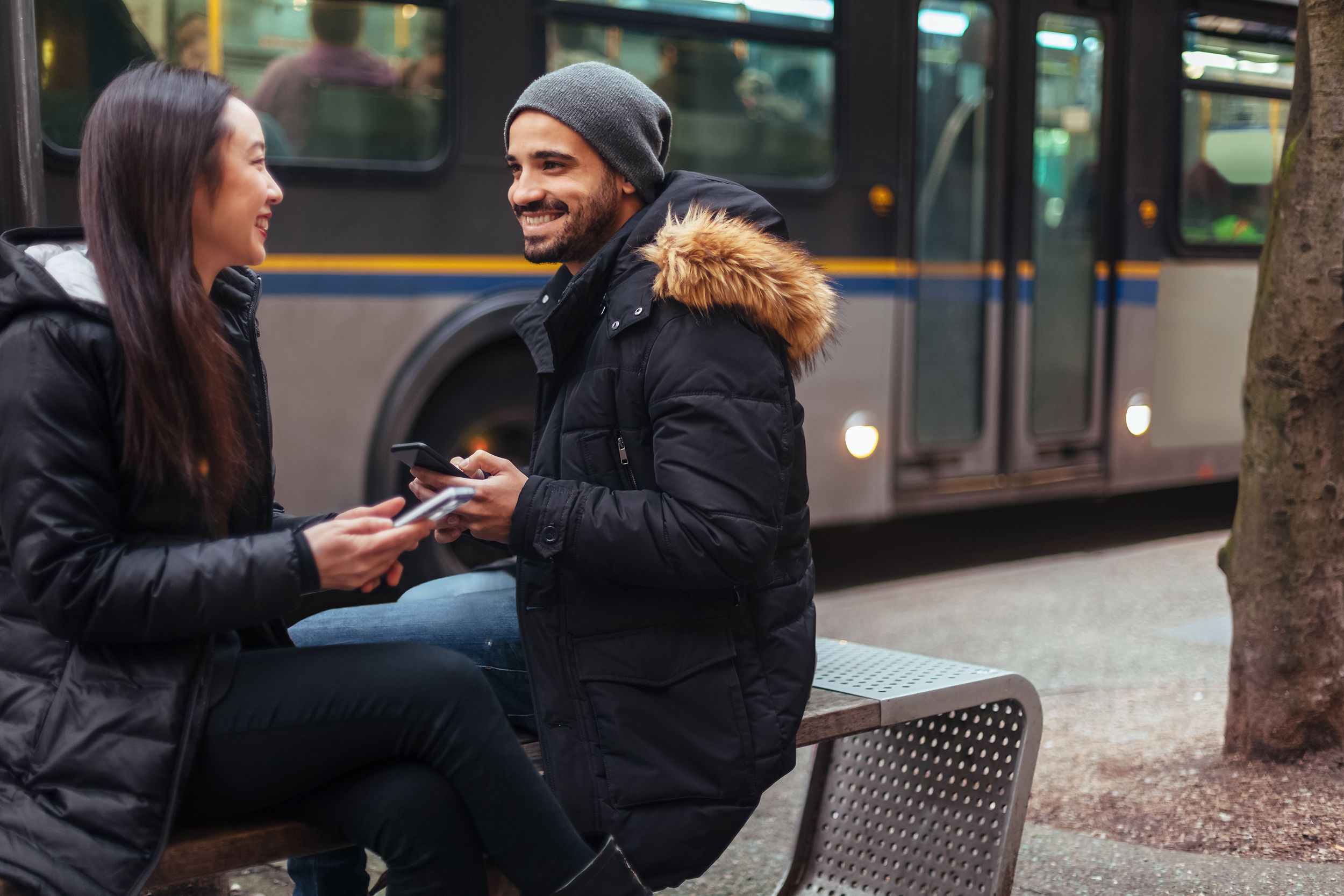 young couple chatting, using smartphone on city street in Vancouver