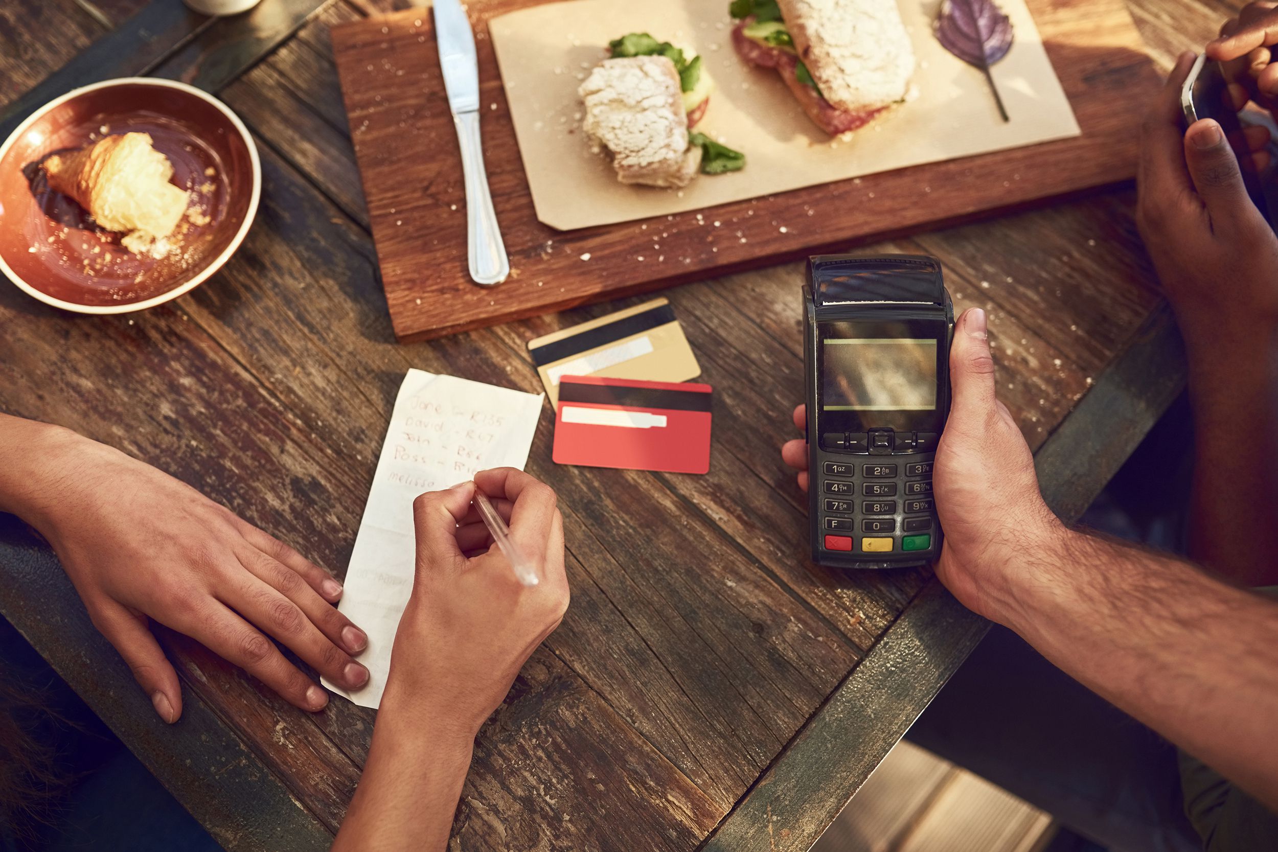 people at restaurant paying at table with portable credit card terminal