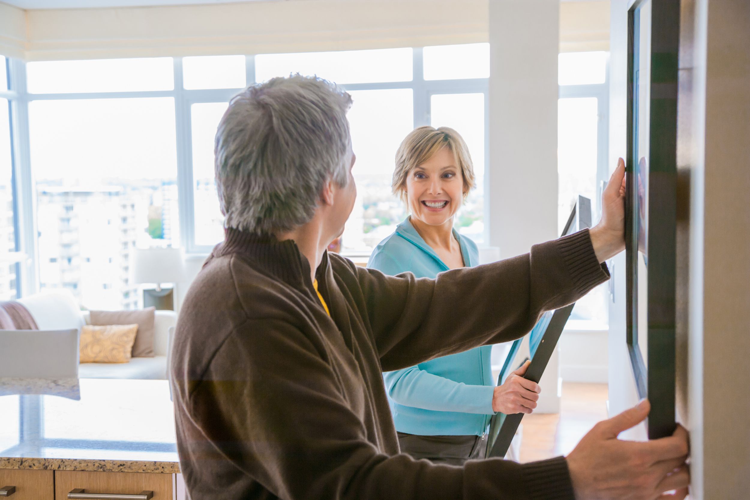couple hanging art in house