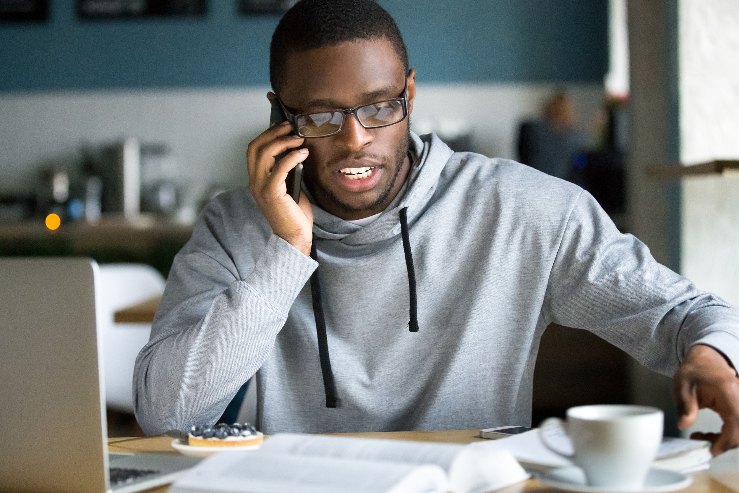 African businessman talking on the phone sitting at cafe table