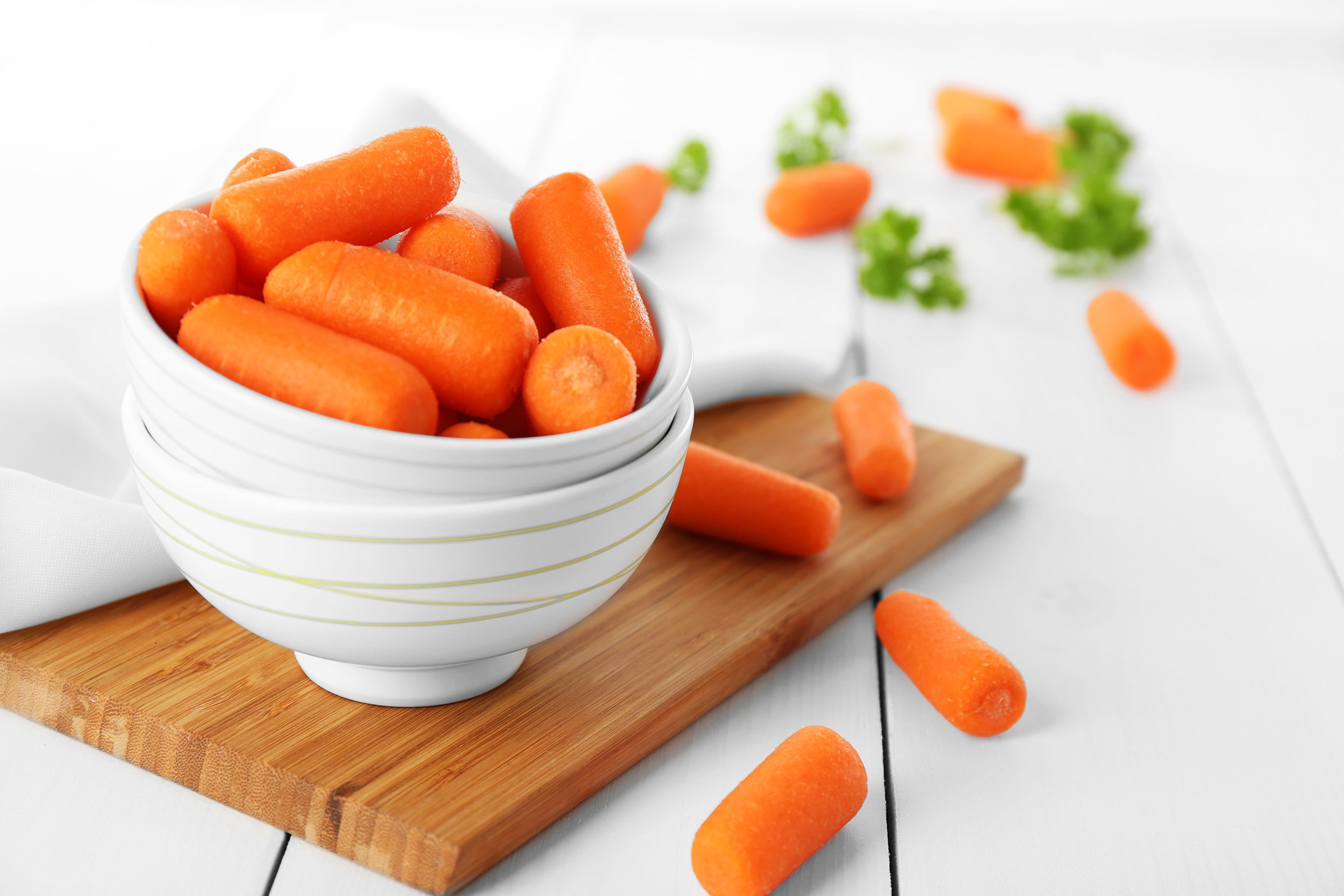 small baby carrots in soup plates on cutting board