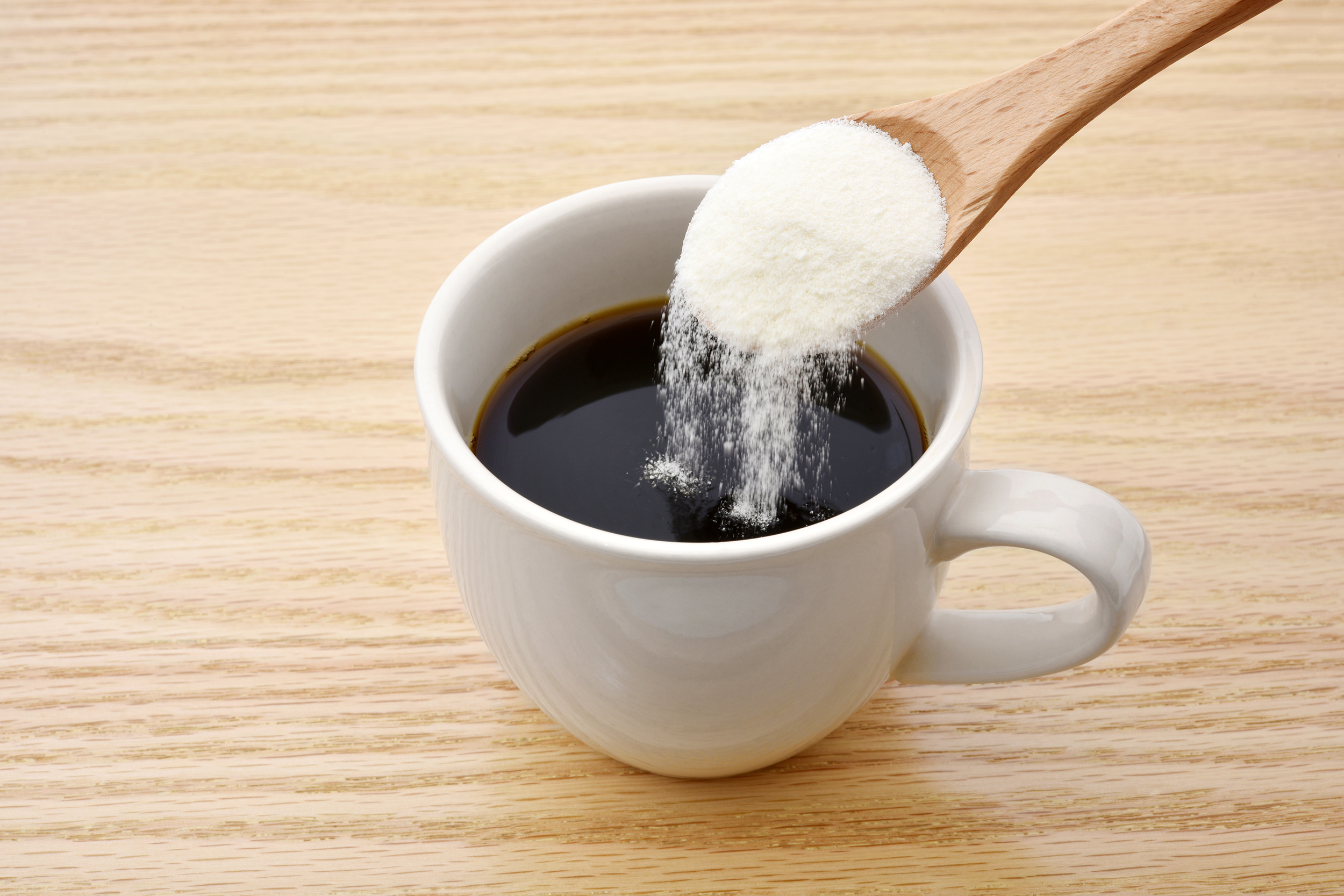 Pouring collagen powder in a cup of coffee
