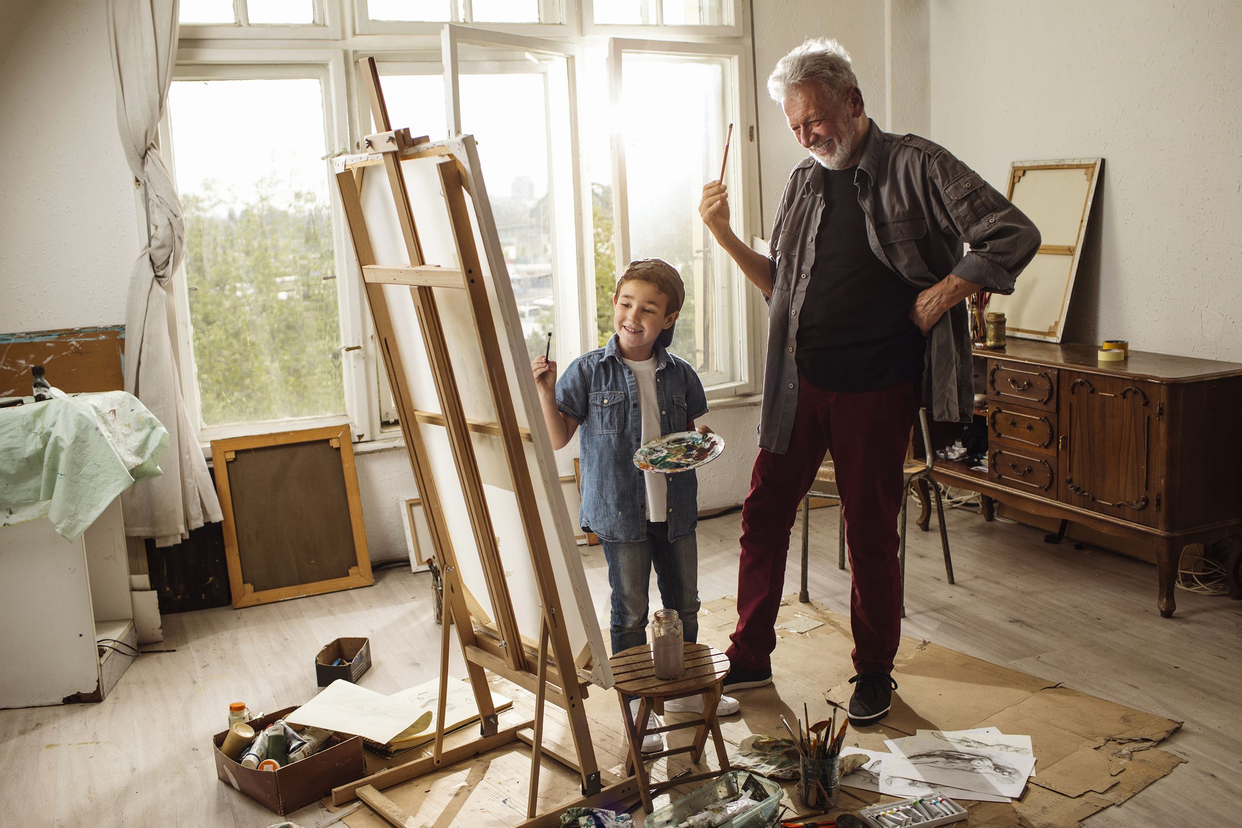 grandfather and grandson painting together in living room