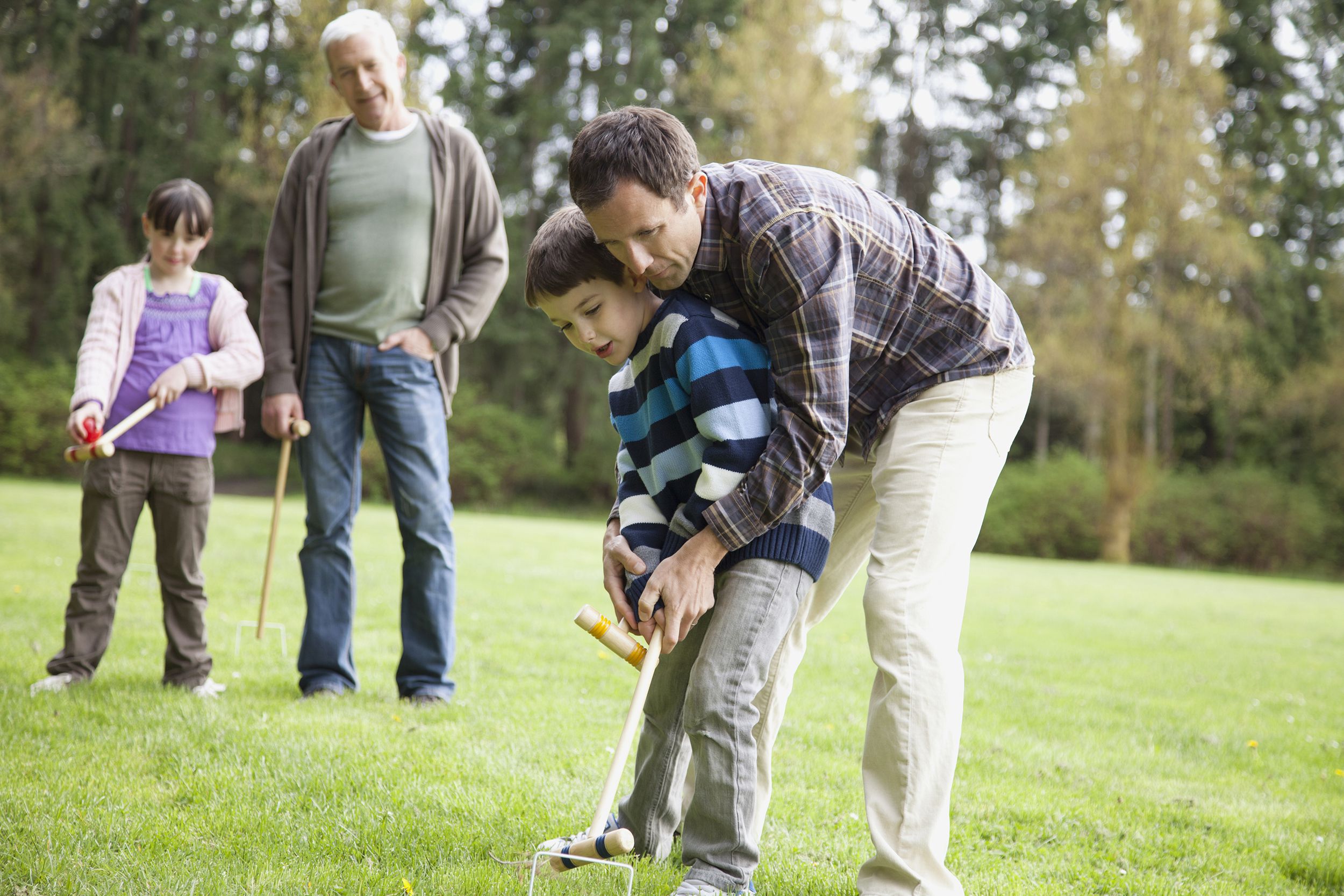 two grandfathers playing croquet with their two grandchildren