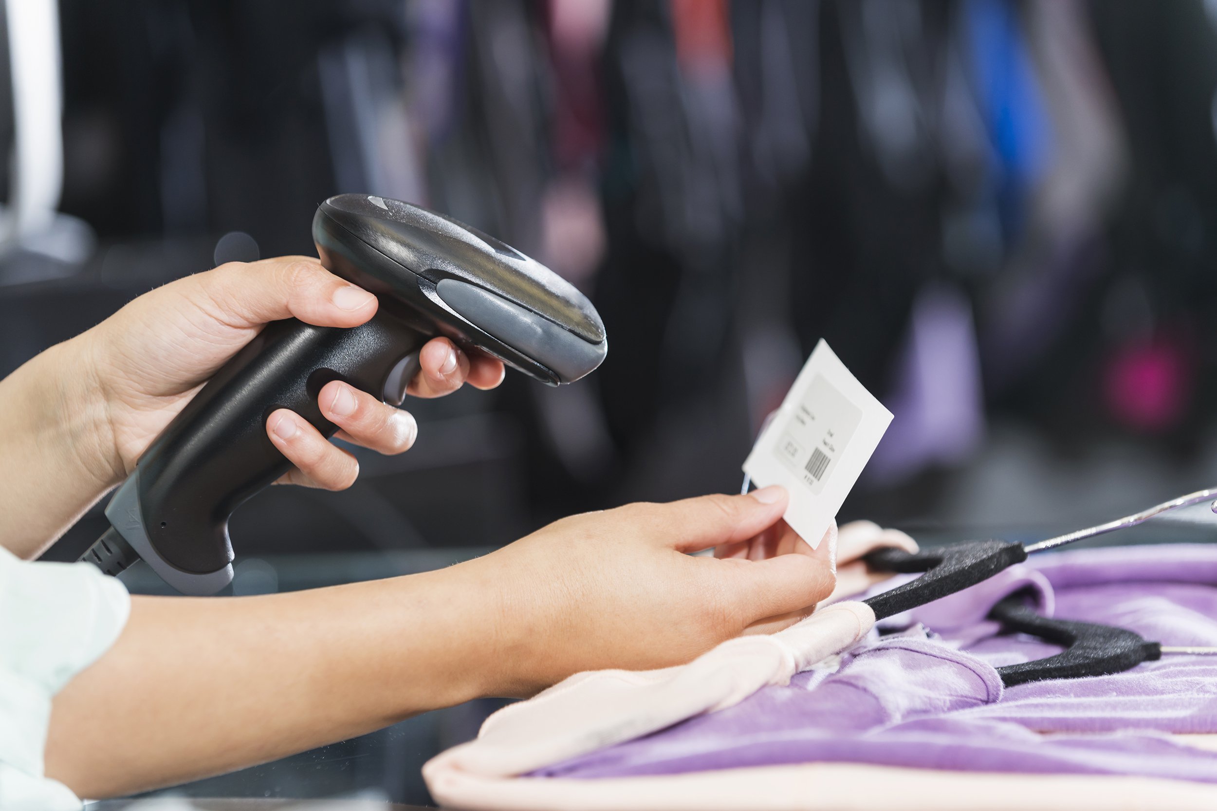 hands using scanner to scan price tag in clothing store