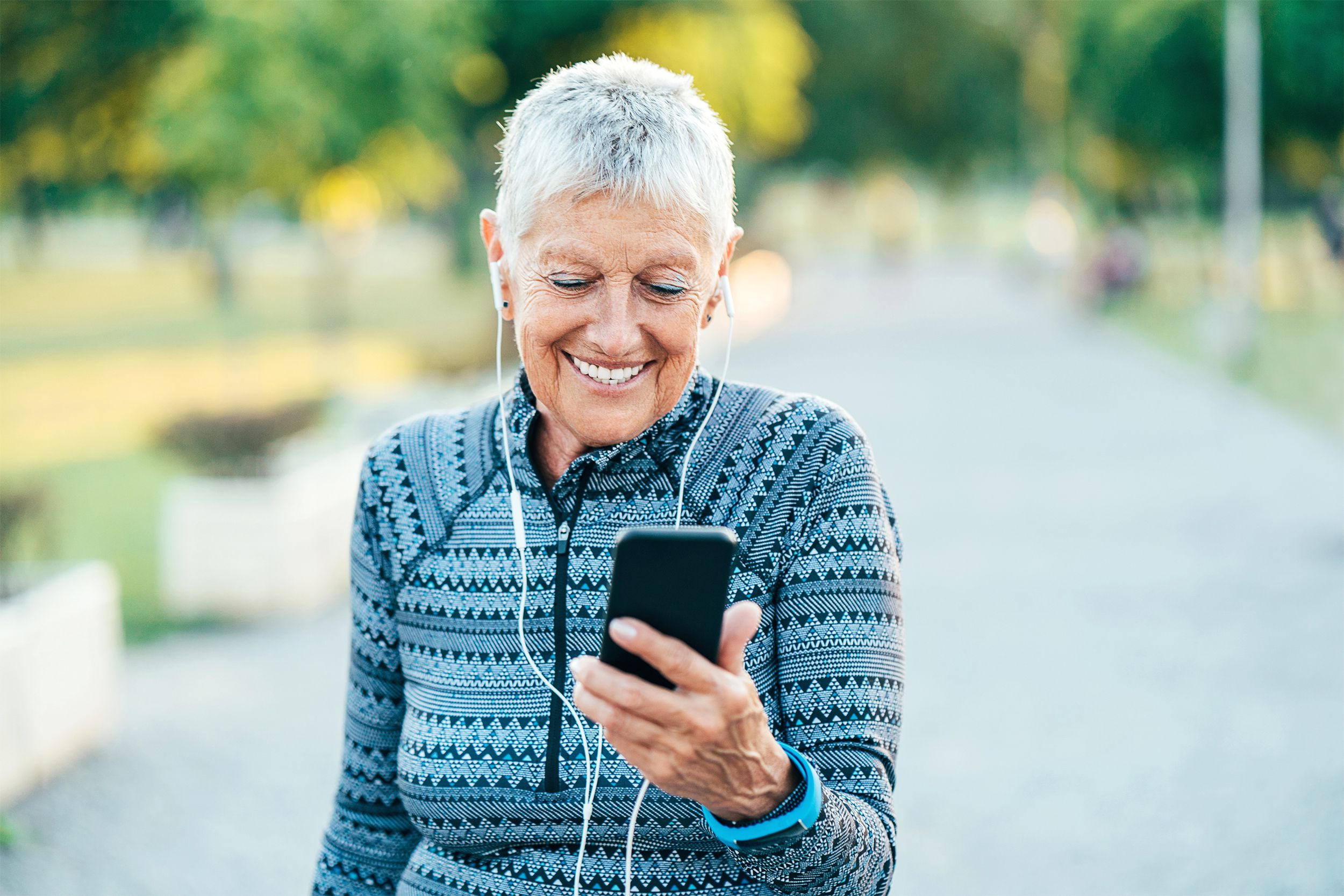 Senior fitness woman looking at her phone outside