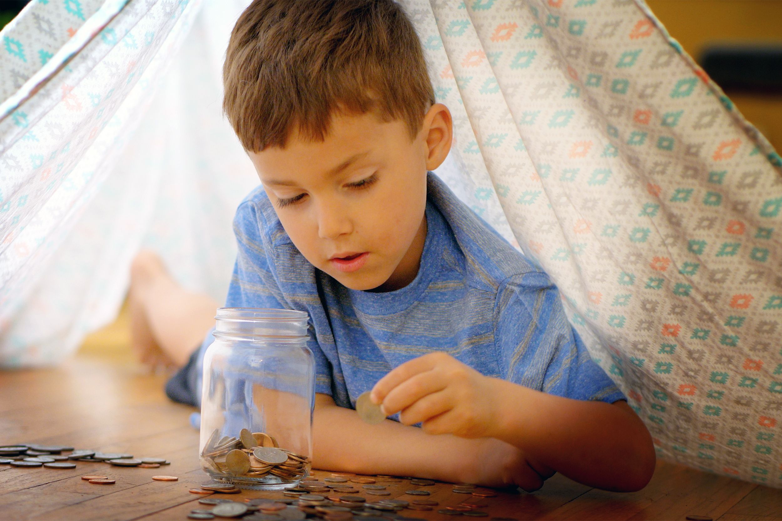 Little boy saving money in a jar