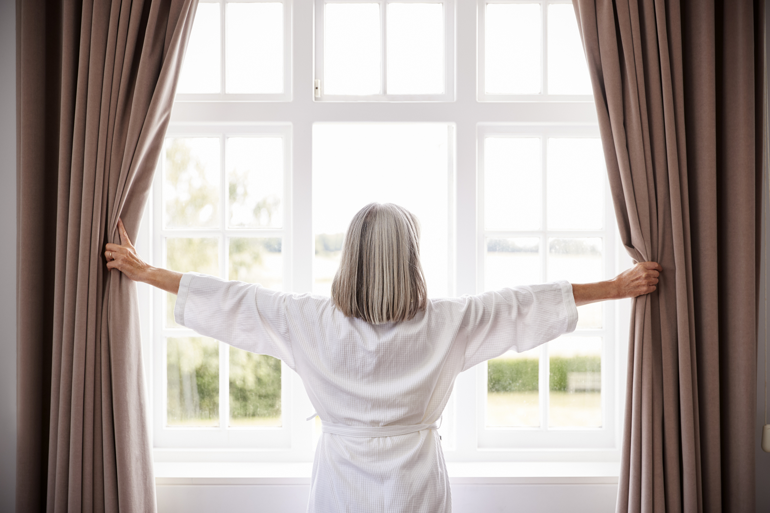 Woman opening bedroom curtains