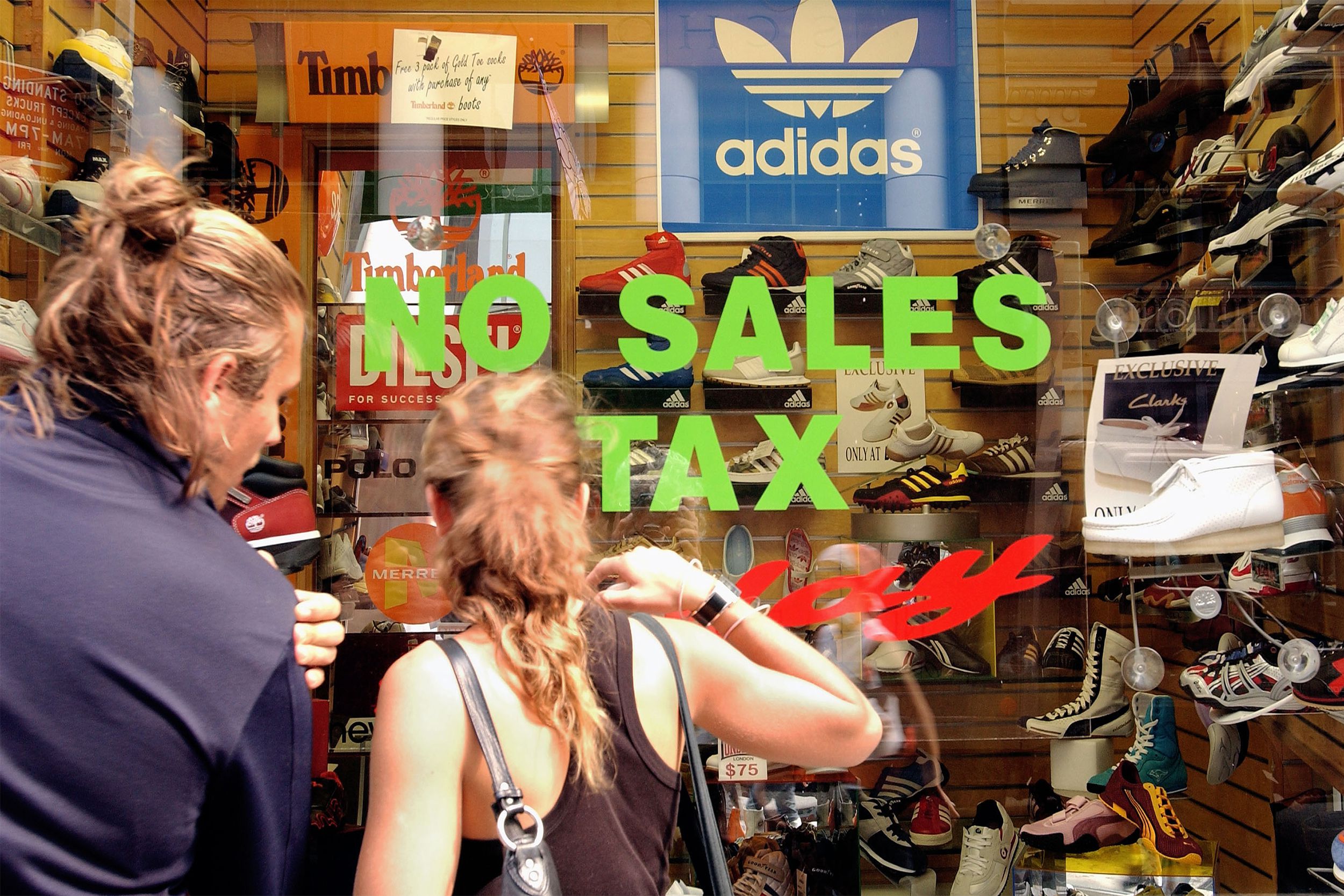 A no tax sign is displayed on a shoe store window