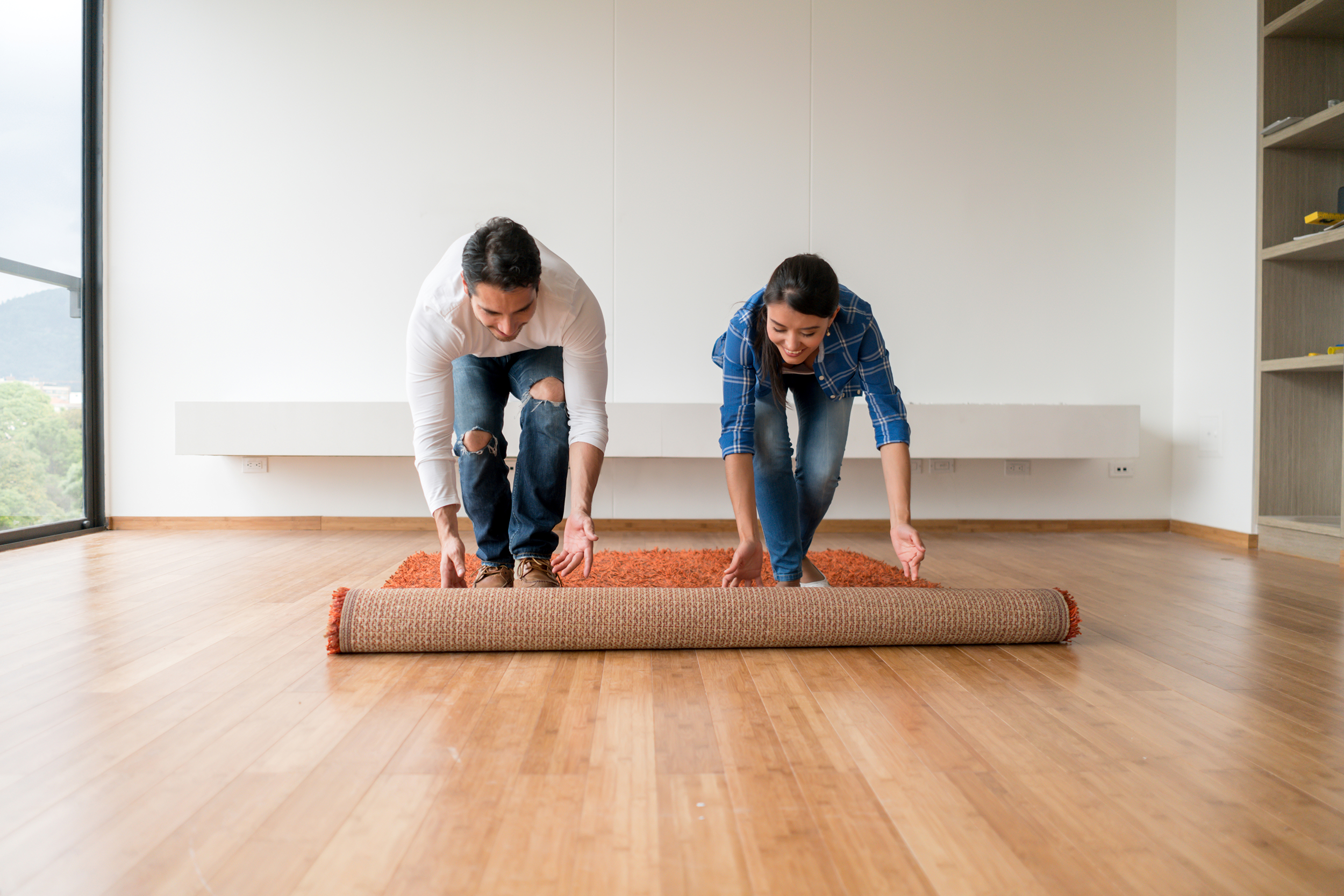 Couple rolling out rug in new empty house
