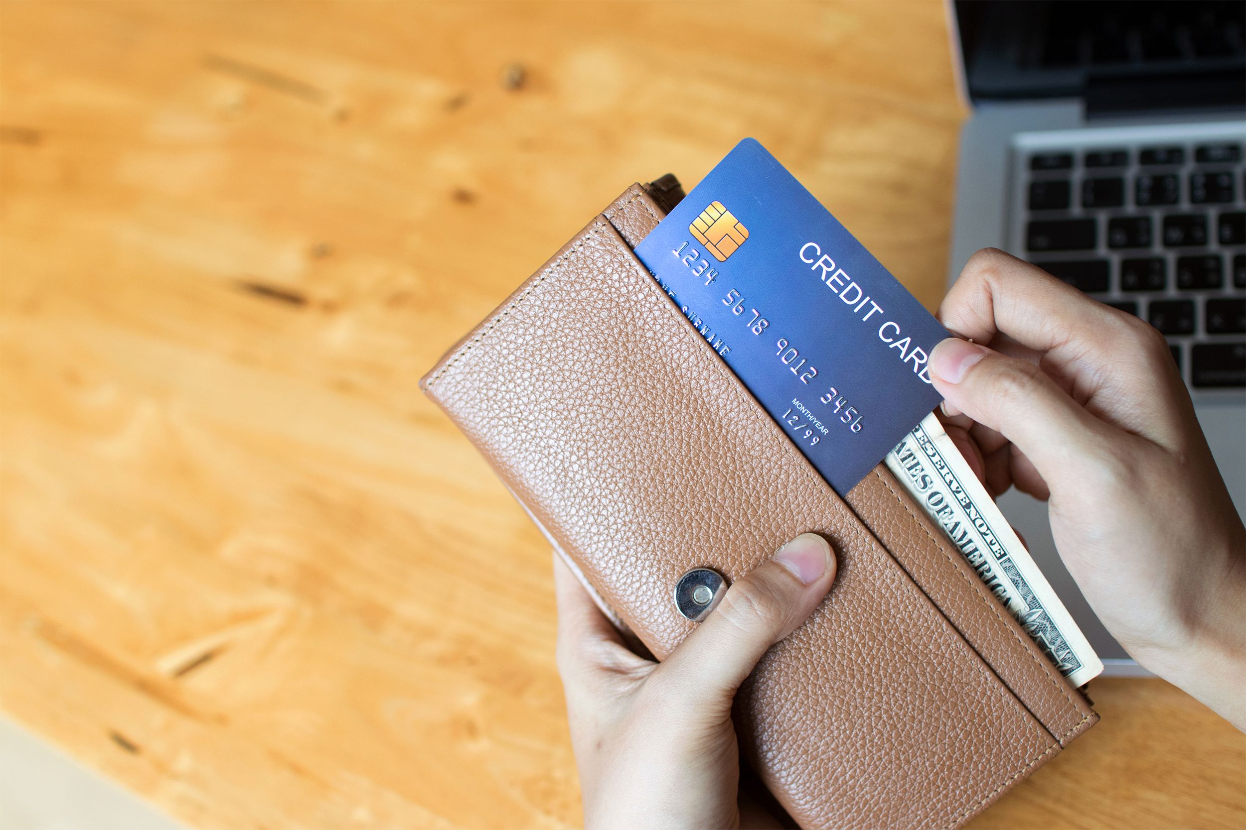 Woman shopping online and paying with a credit card from the wallet.