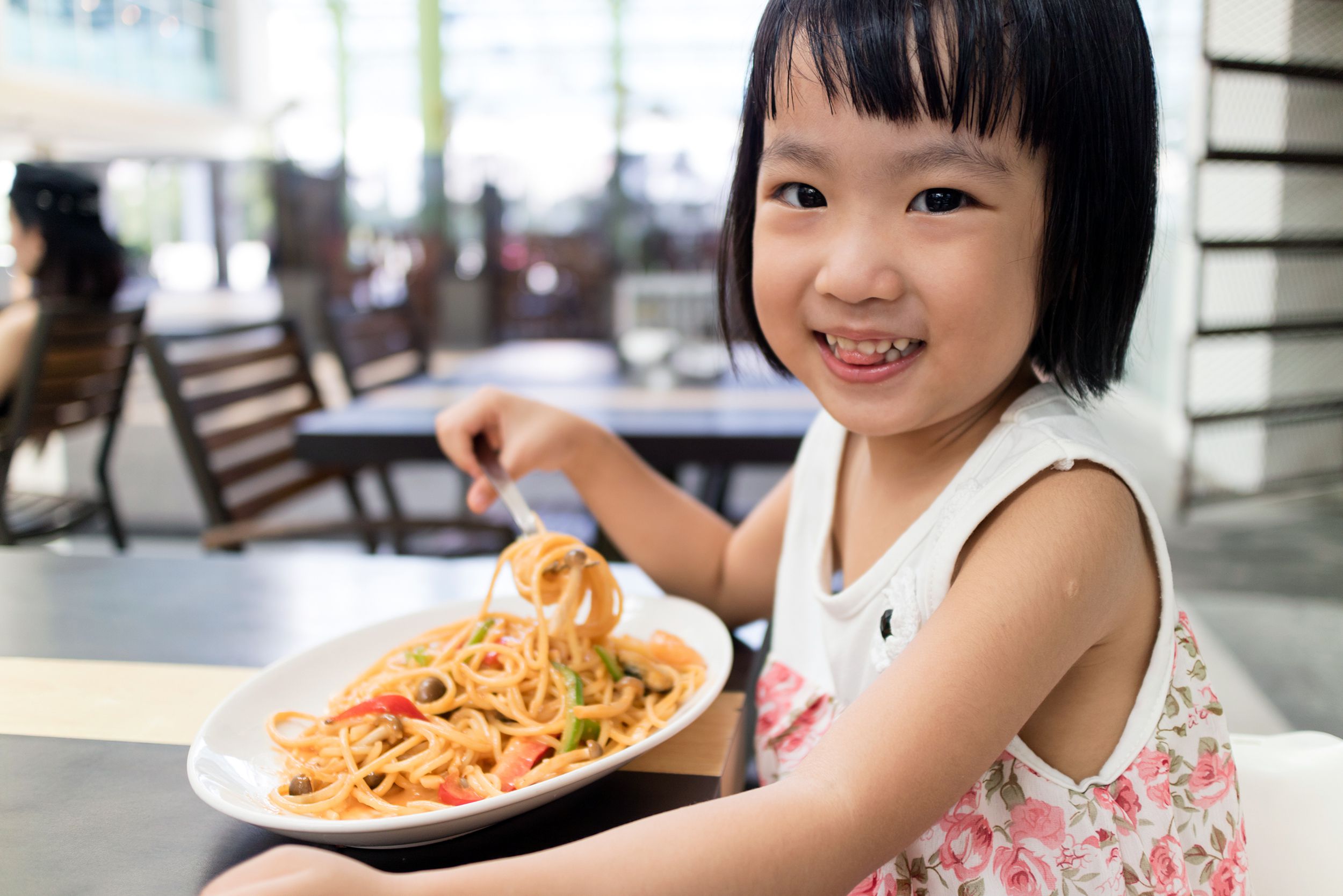 Little girl eating noodles at a restaurant