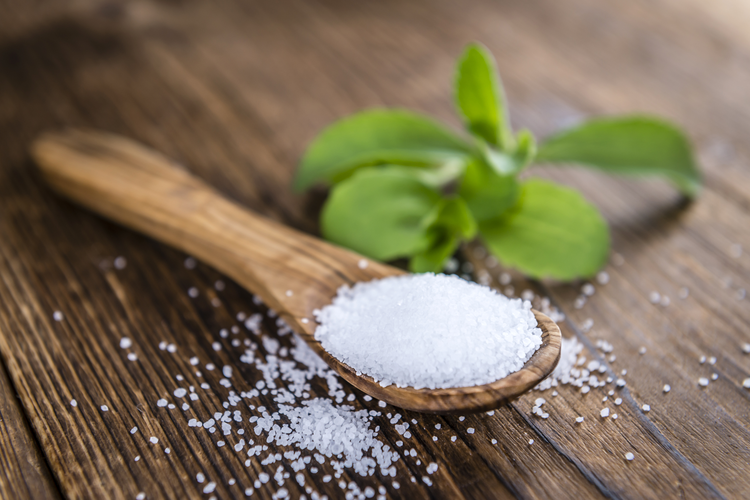 Stevia in a wooden spoon next to the plant