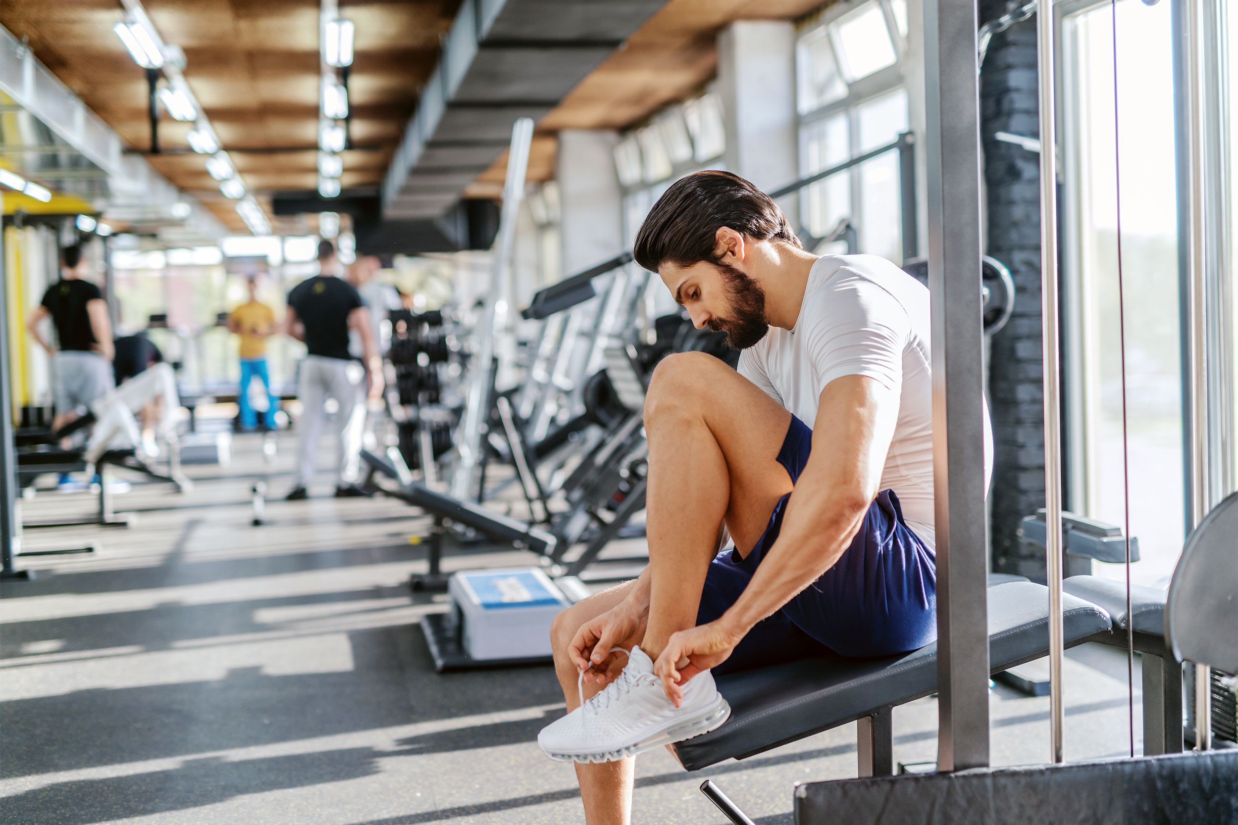 Hipster man tying his shoes at the gym