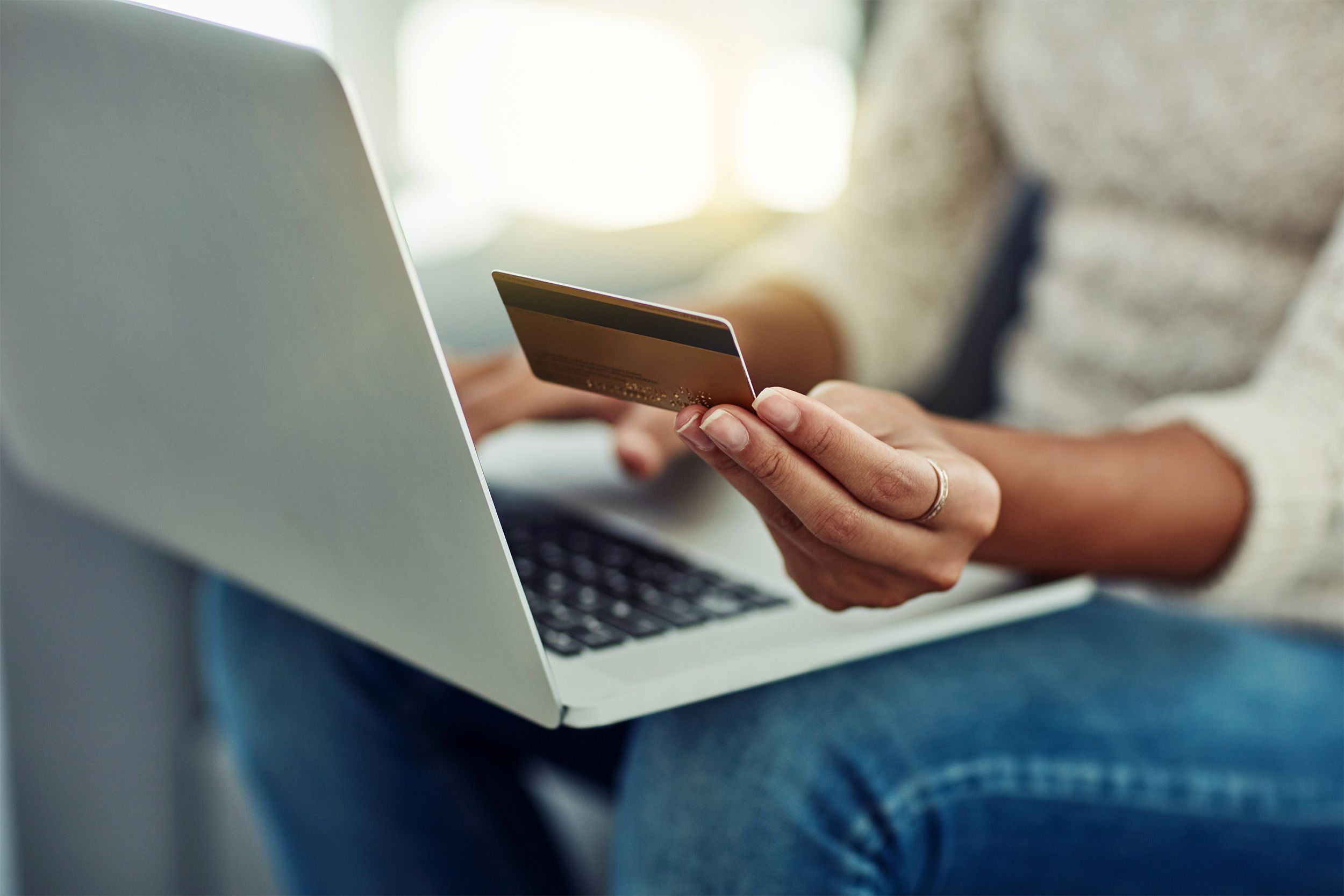Closeup of woman holding credit card and using her laptop
