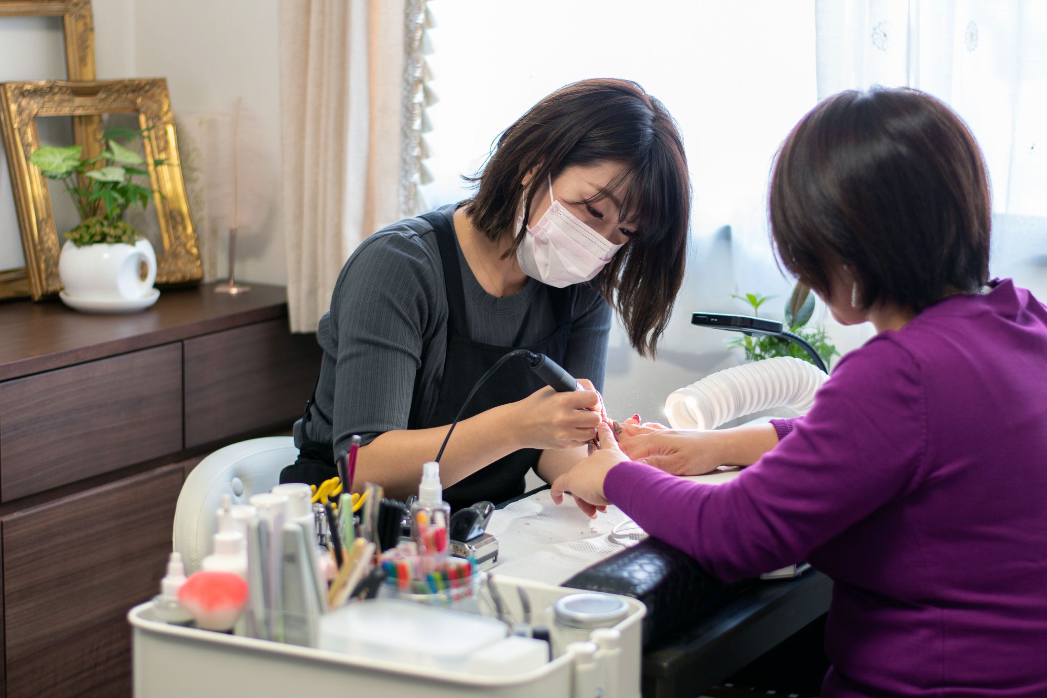 manicurist working on nails at nail salon