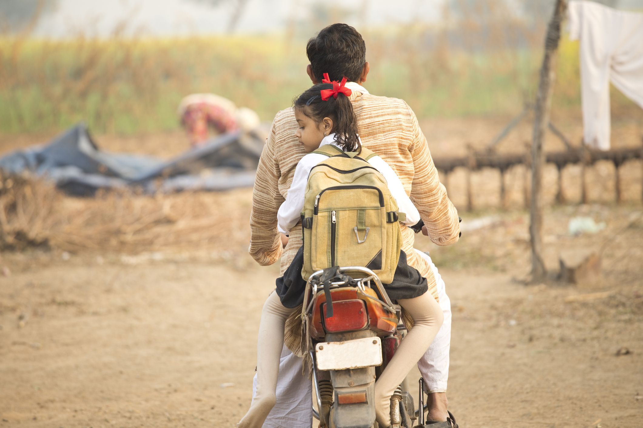 father taking daughter to school on motorbike