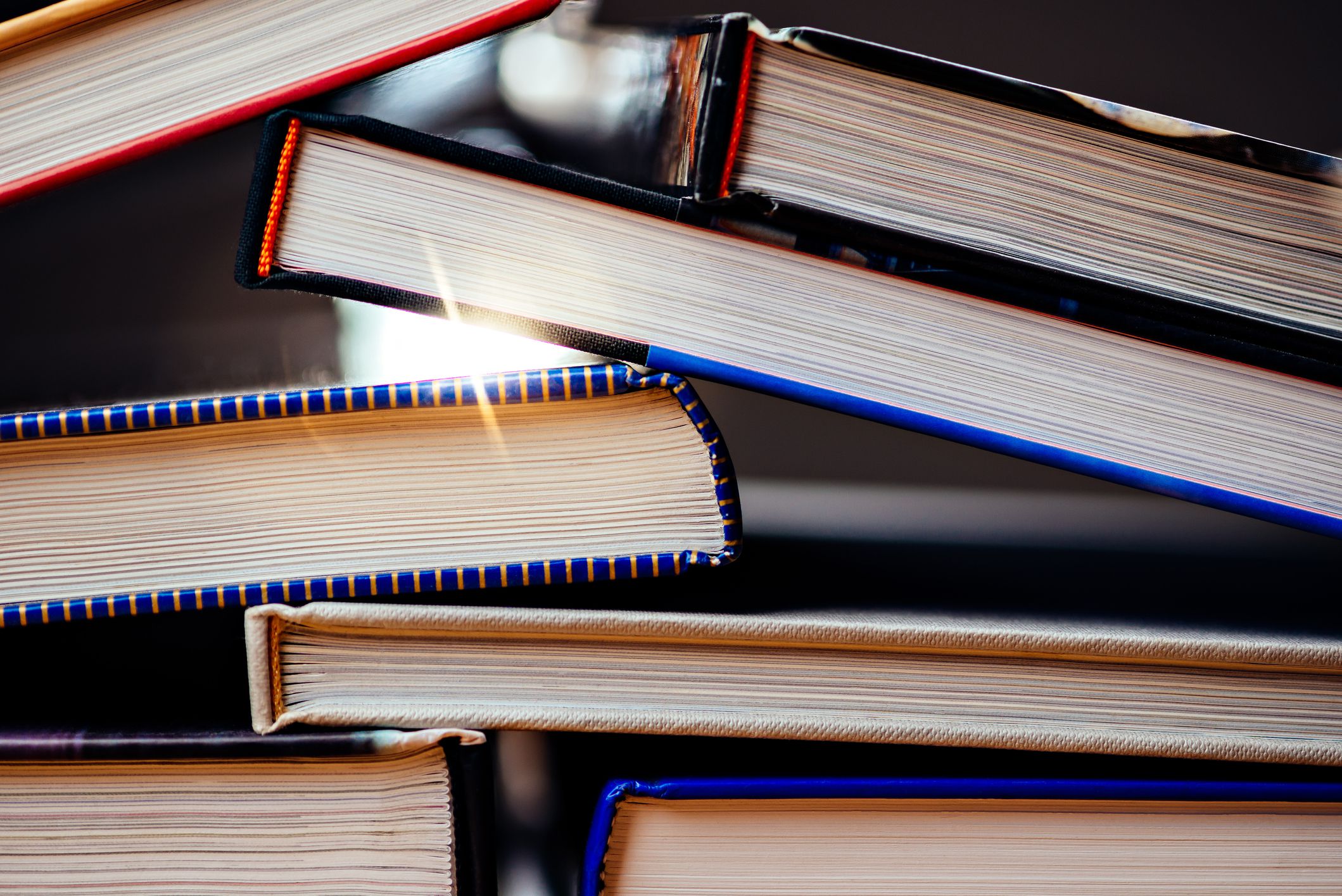 college textbooks piled on a stack, with sunlight shining through