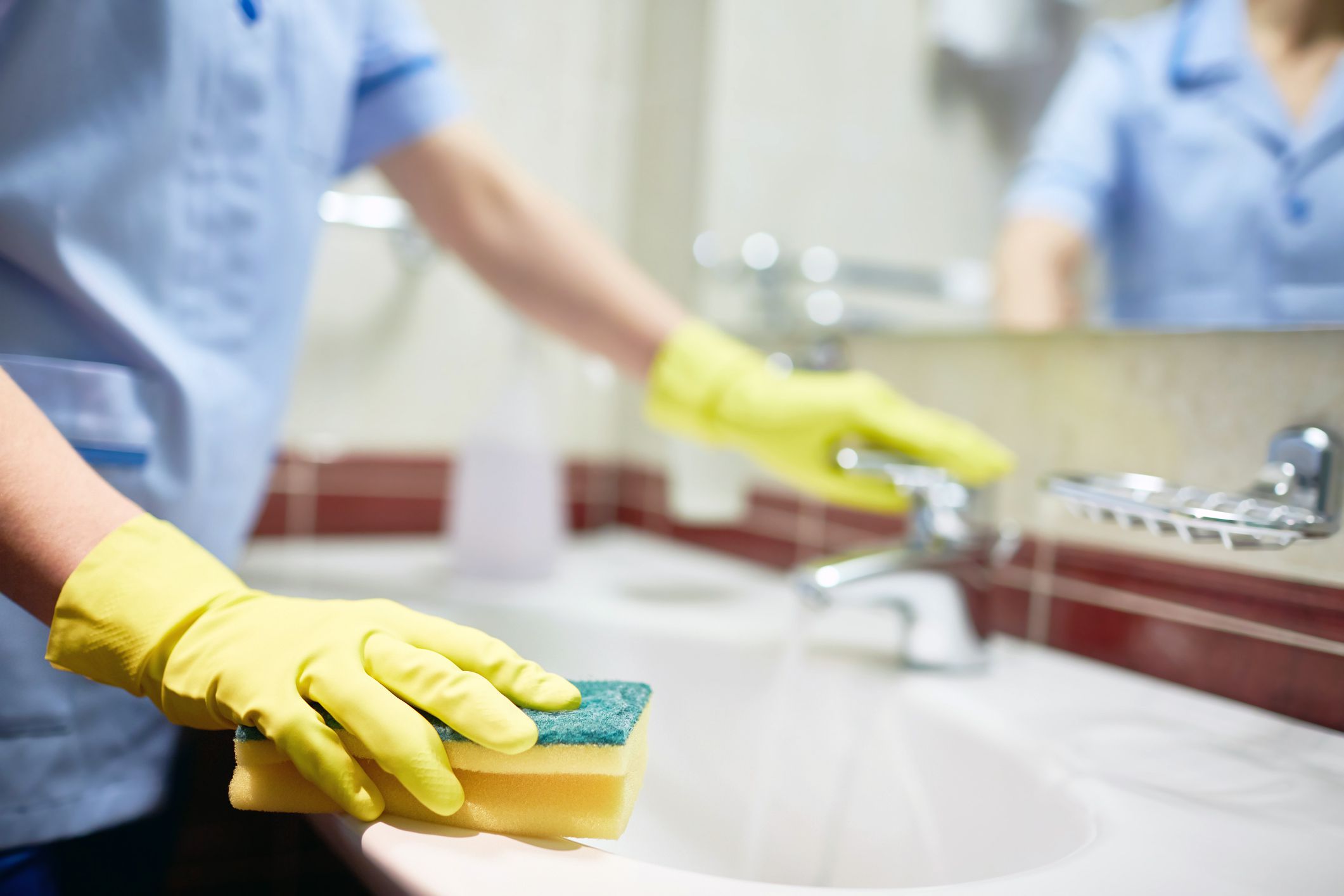 close-up of maid cleaning sink in hotel bathroom